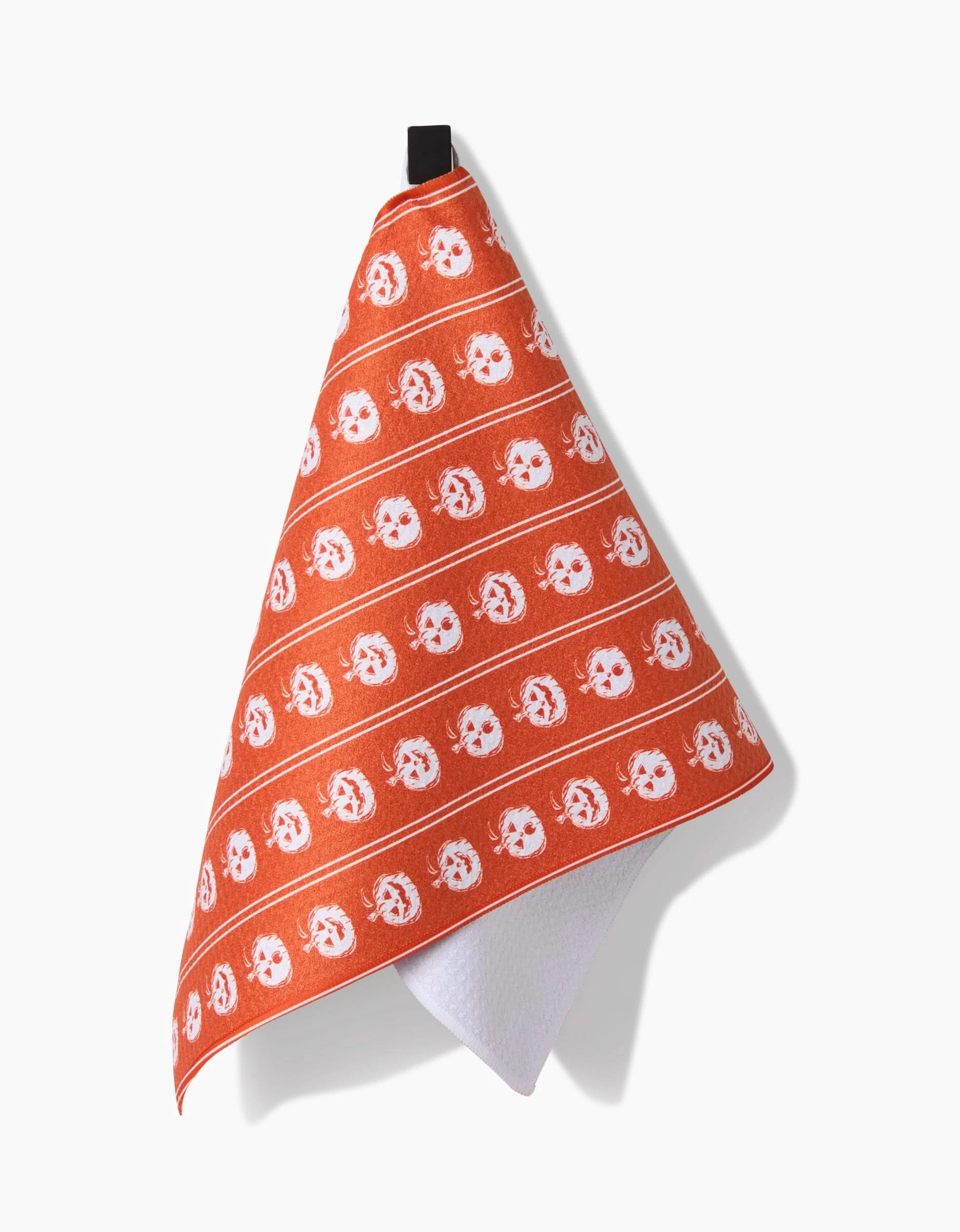 The Aubrey Fairchild Pumpkin Pinstripes bar towel is ultra-absorbent, featuring orange fabric with white cartoon cat faces and horizontal lines, and hangs by a black loop against a white background.
