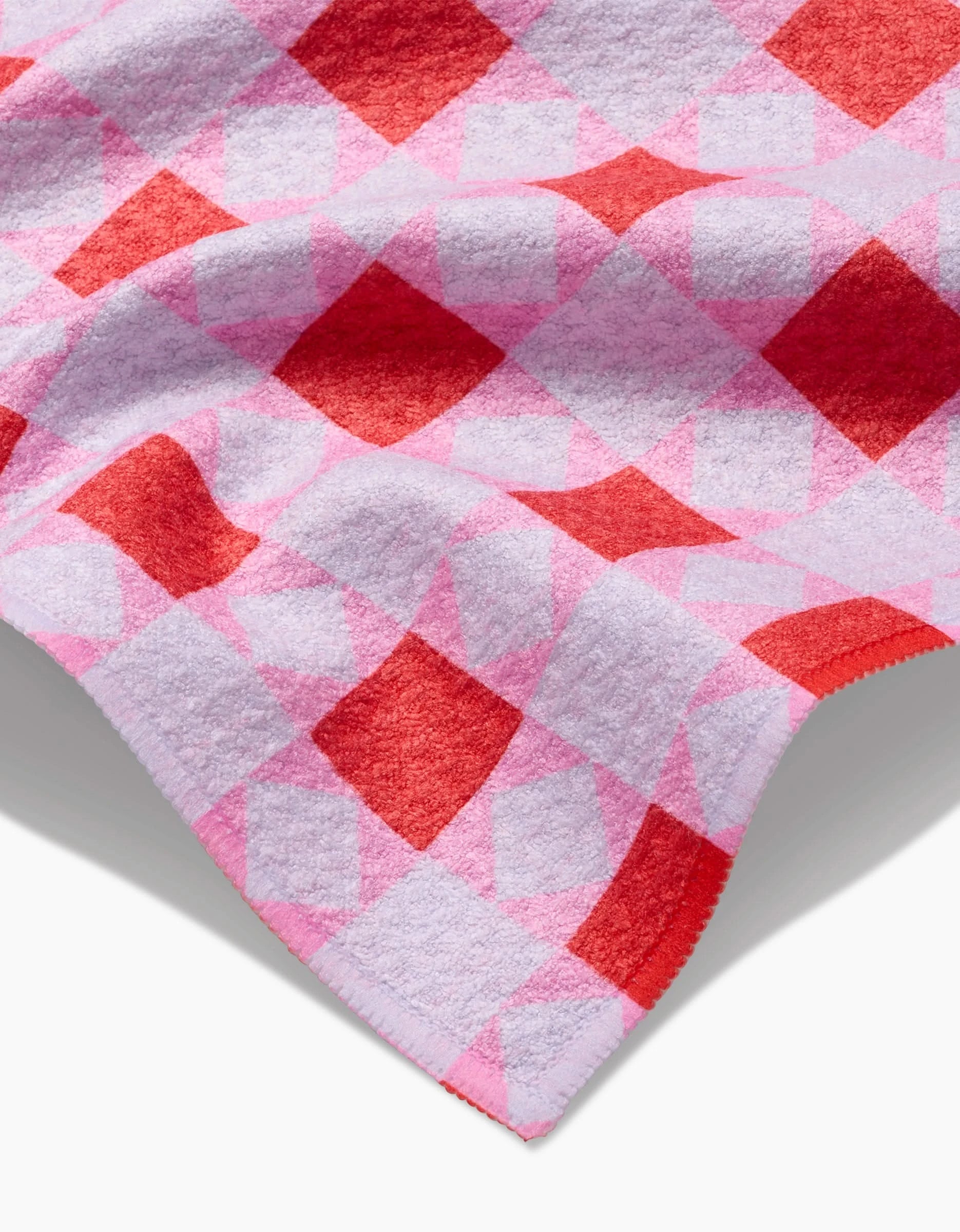 A close-up of the Quilt Block Pink Andred Bar Towel by Brittany Jepsen, showcasing its pink and red diamond Geoweave fabric with soft folds that highlight the textured pattern against a light background.