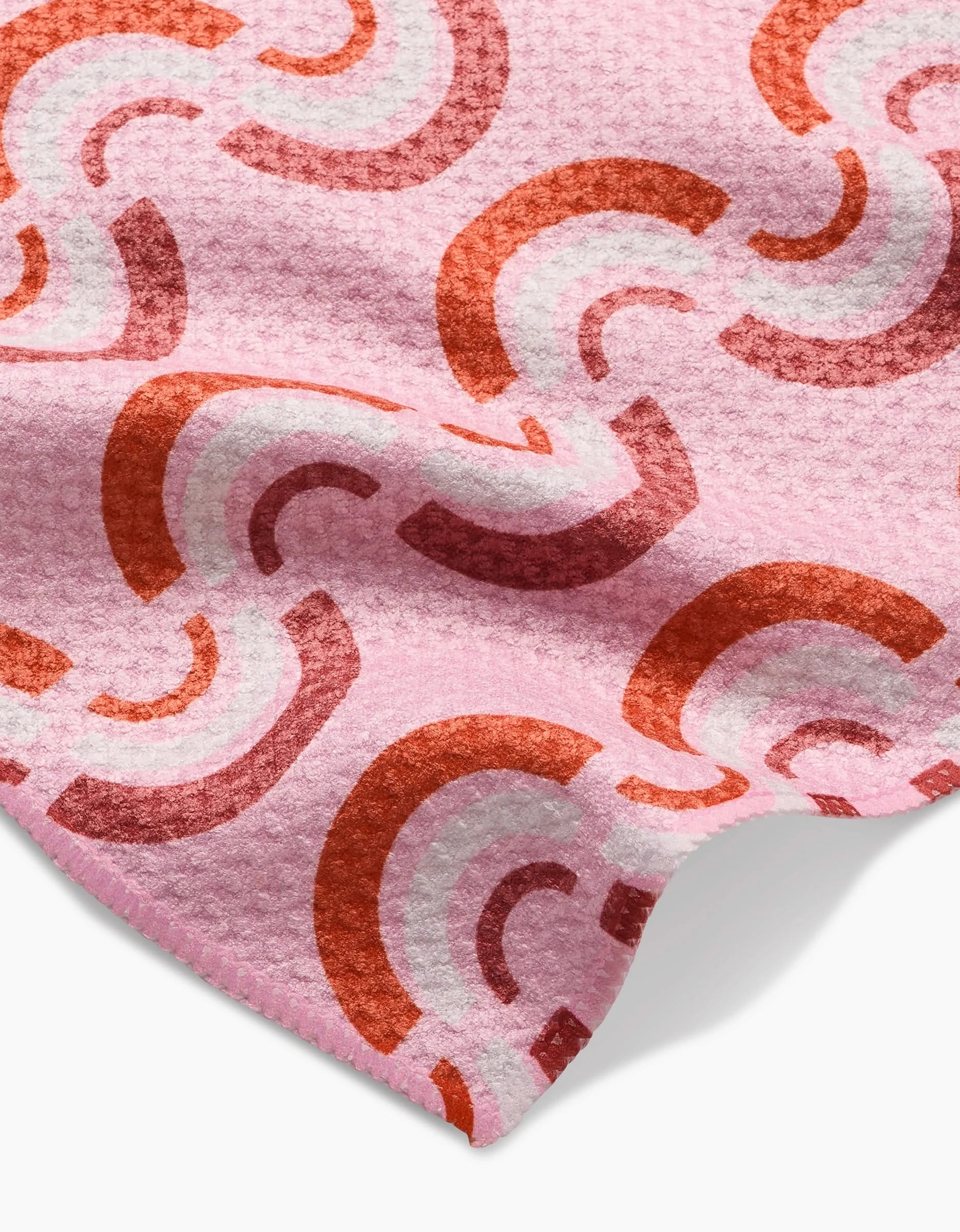 Rainbow Waves by Whitney Urquhart is a pink Geoweave™ bar towel with a retro rainbow pattern in red, orange, and white. Slight folds highlight its soft texture and vibrant design.