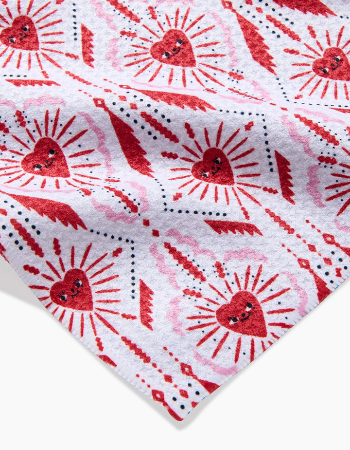 The Ray of Love towel by Roxy Marj features a white fabric adorned with playful red hearts, radiating lines, dots, and abstract designs in red, pink, and black. Ultra-absorbent and made from recycled materials.