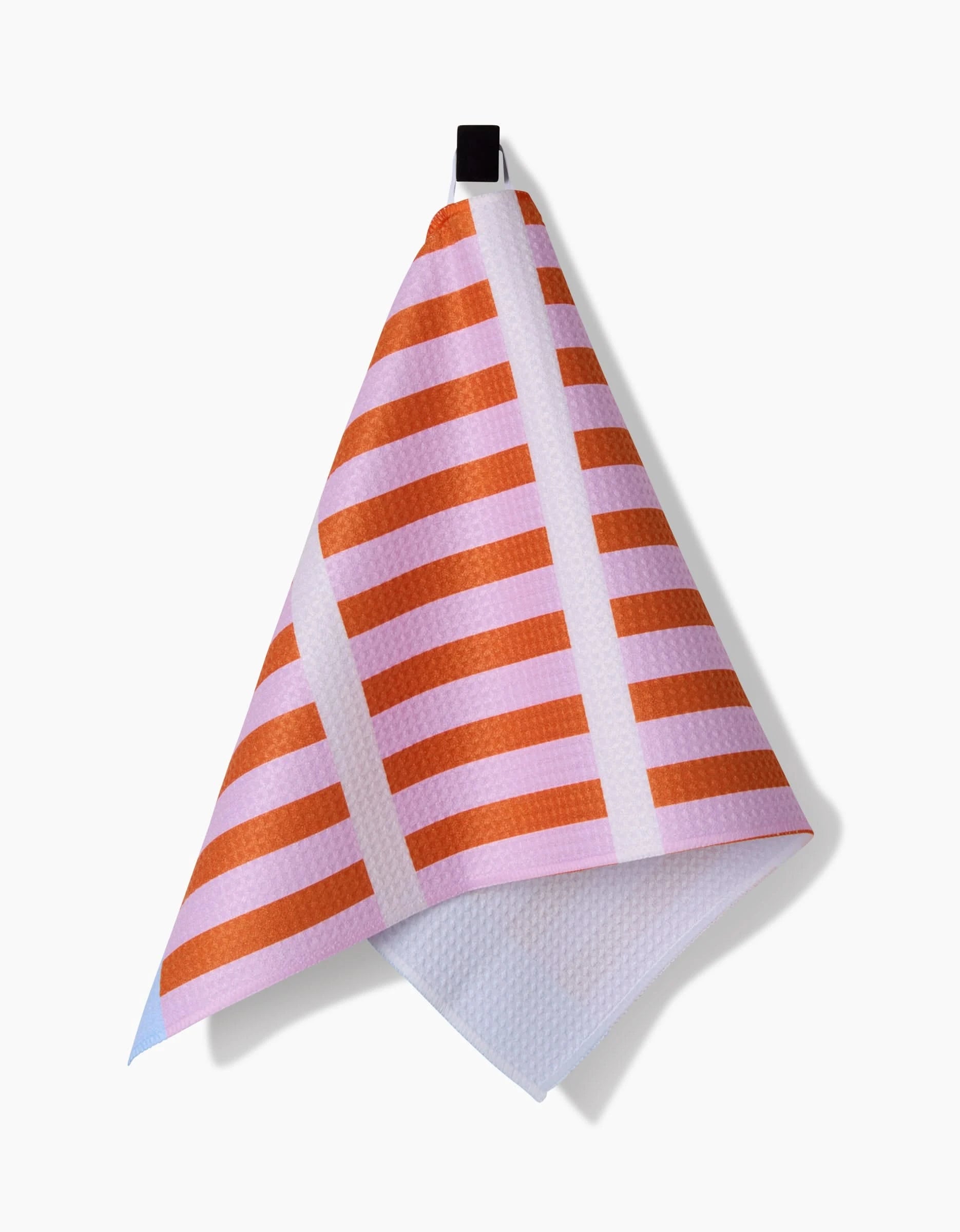 The Red Glow Bar Towel by Happy Hemera, crafted from soft Geoweave fabric, features orange horizontal stripes and white lines on a pink background, and hangs from a black loop against a white backdrop.