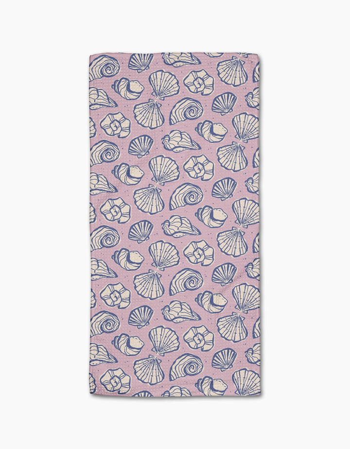 The Retro Coastal Seashells in Pink towel by Teri the Butter is a rectangular, light pink ultra-absorbent towel with blue and white seashell patterns on a white background.
