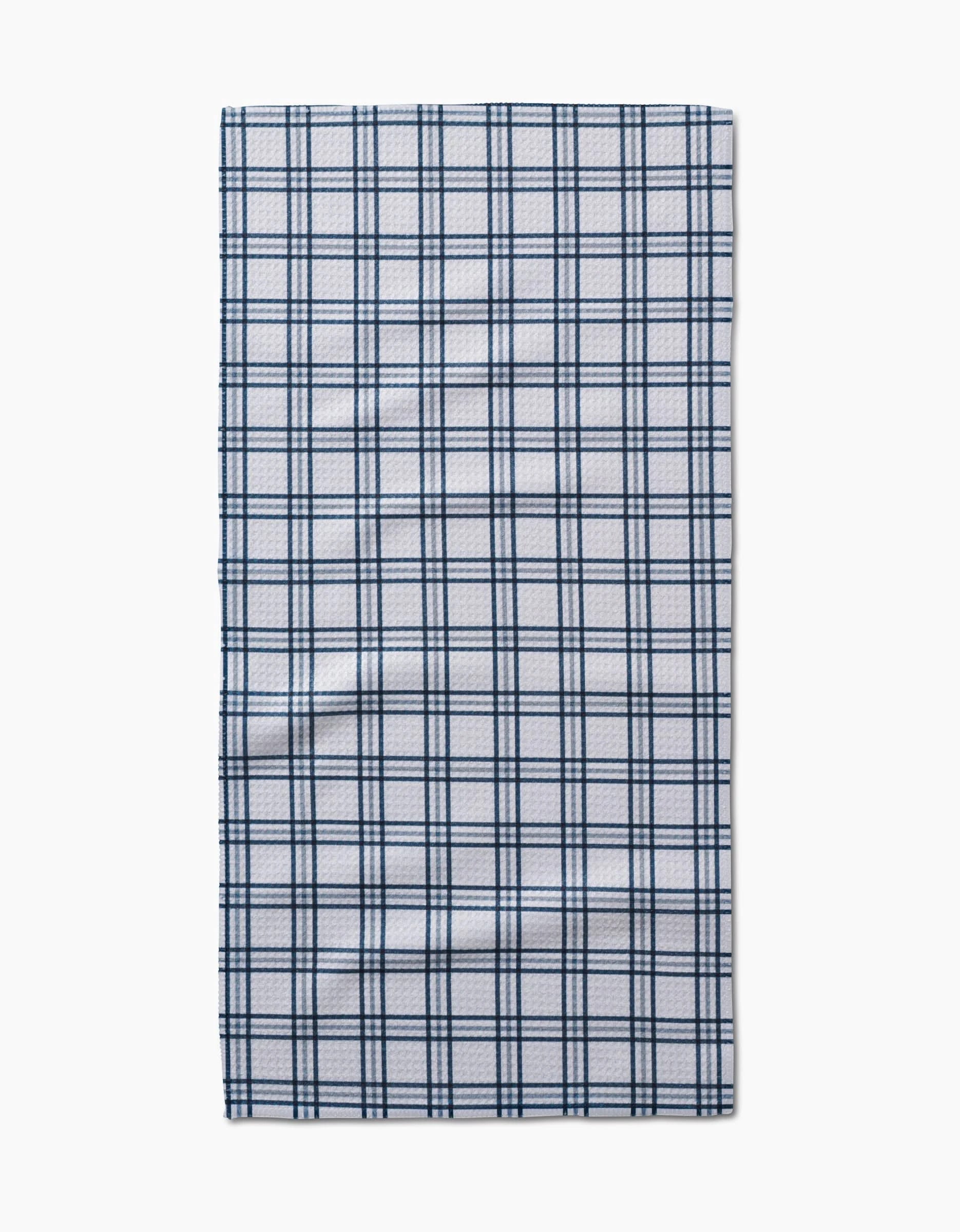 The Roma bar towel by Kelsi Fullmer is a rectangular, white Geoweave fabric towel with a dark blue plaid pattern of evenly spaced lines, shown laid flat on a plain white background.