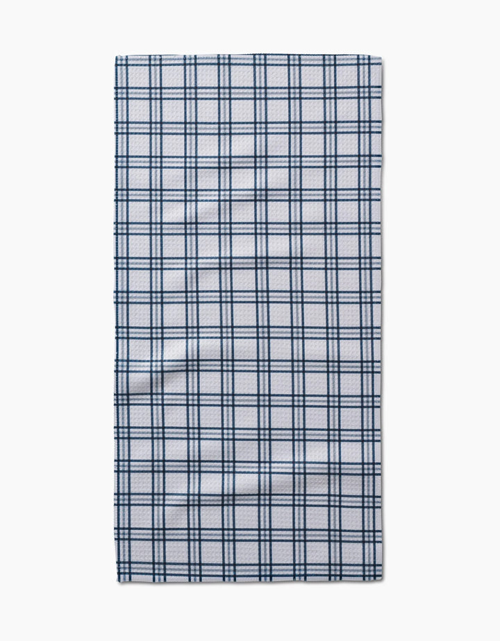 The Roma bar towel by Kelsi Fullmer is a rectangular, white Geoweave fabric towel with a dark blue plaid pattern of evenly spaced lines, shown laid flat on a plain white background.