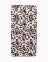 The Rustic Lacy Tile Natural by Hufton Studio is a rectangular white recycled kitchen towel with a repeating brown and gold botanical pattern of symmetrical tree motifs arranged in rows.