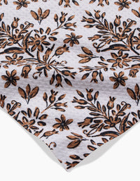 A close-up of the Rustic Lacy Tile Natural by Hufton Studio, a white ultra-absorbent towel with a brown and black floral pattern of densely arranged leaves and small flowers.