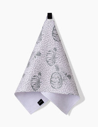 The Sage Pumpkin Field Bar Towel by Charlie Rowan Designs, crafted from Geoweave fabric, features gray pumpkin illustrations and dotted patterns. It hangs from a black loop against a white background.