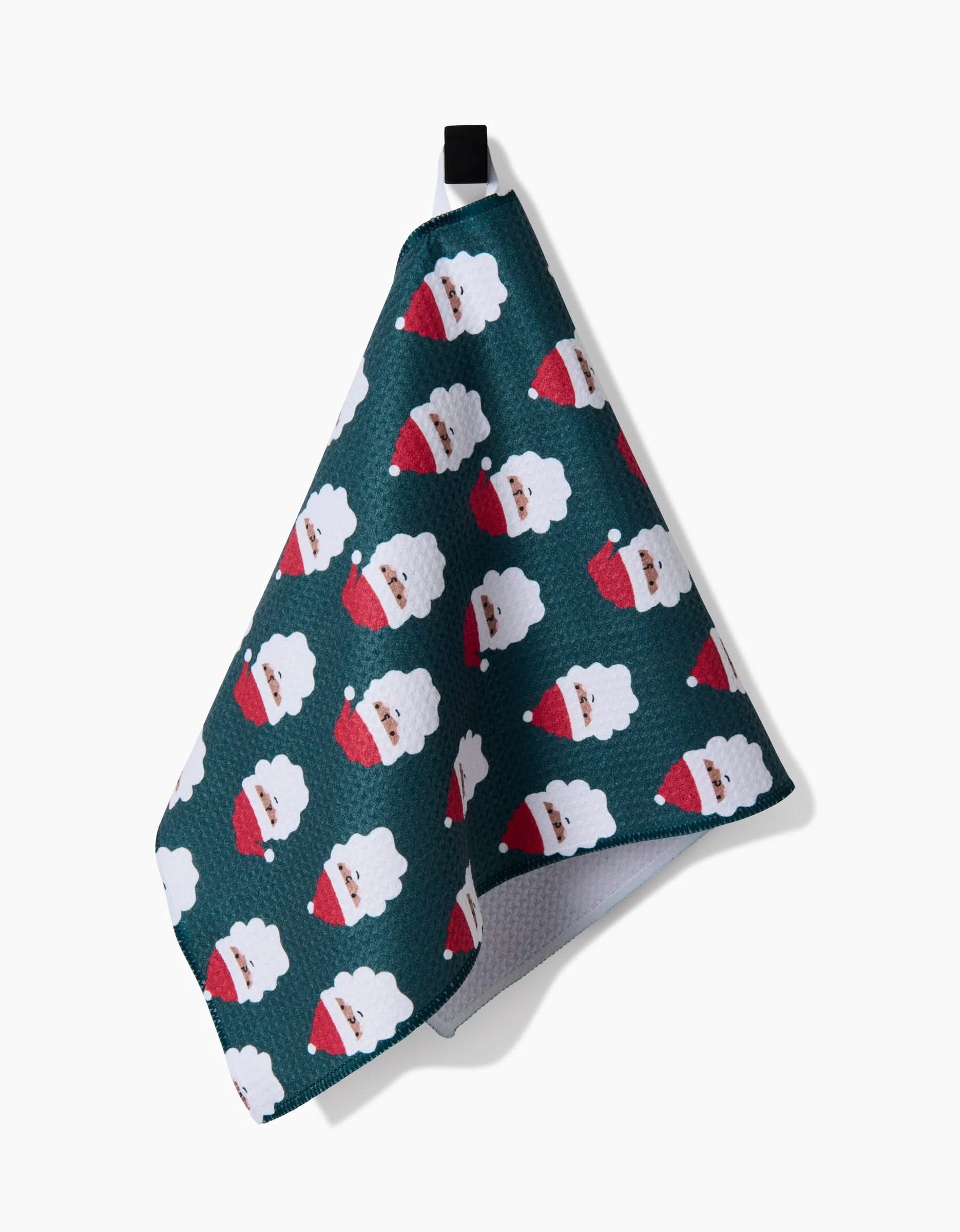 The Santa Santa kitchen towel by Charlie Rowan Designs is green, ultra-absorbent, features repeating Santa faces, is made from recycled materials, and hangs from a black loop.