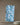 The Geometry Seaglass ultra-absorbent towel in a blue and white pattern hangs from a clothesline with wooden clothespins, above a stack of white plates on a gray surface.