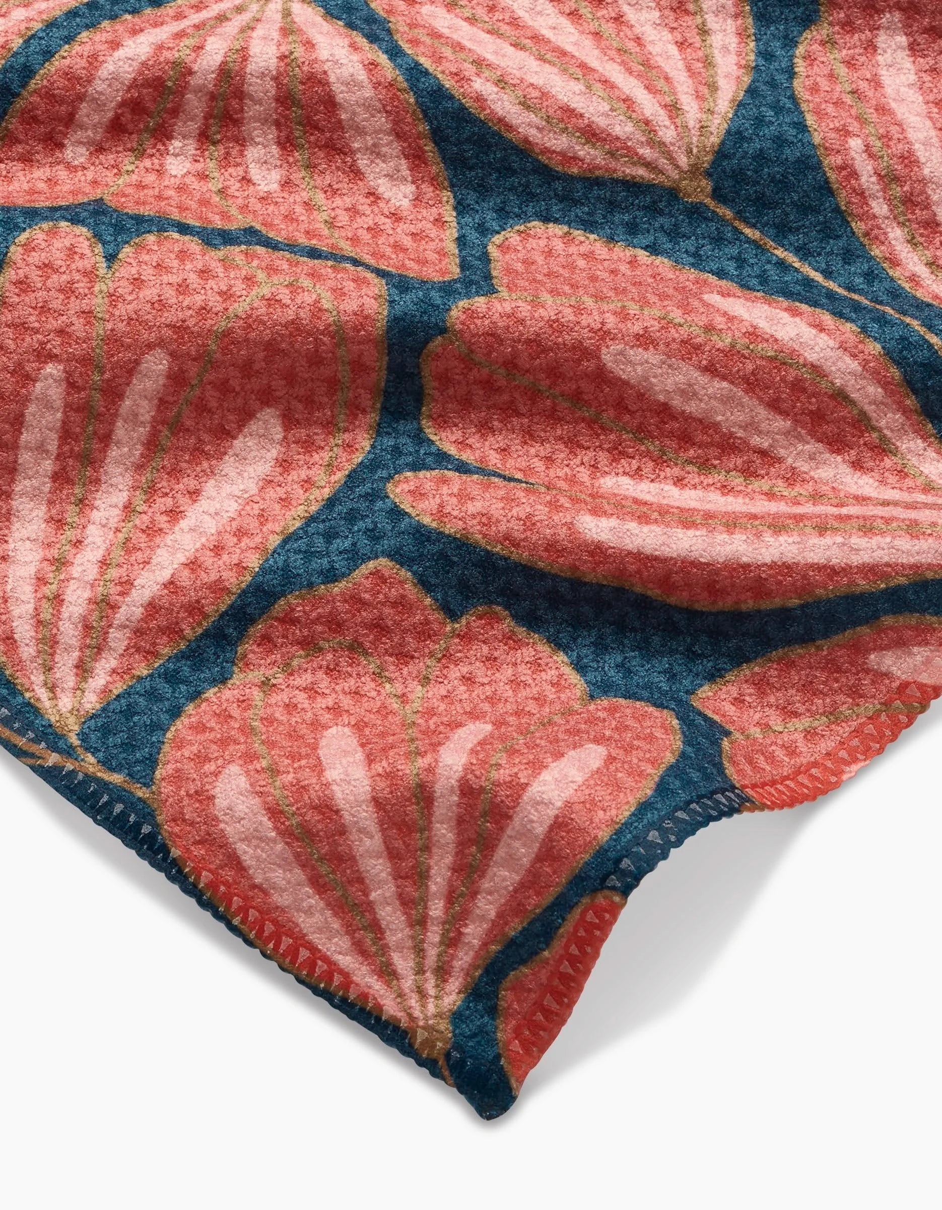Close-up of Amy MacCready’s Sheila Geoweave fabric, featuring large pink stylized flower petals on a dark blue background, with visible neat coral stitching along the edge.