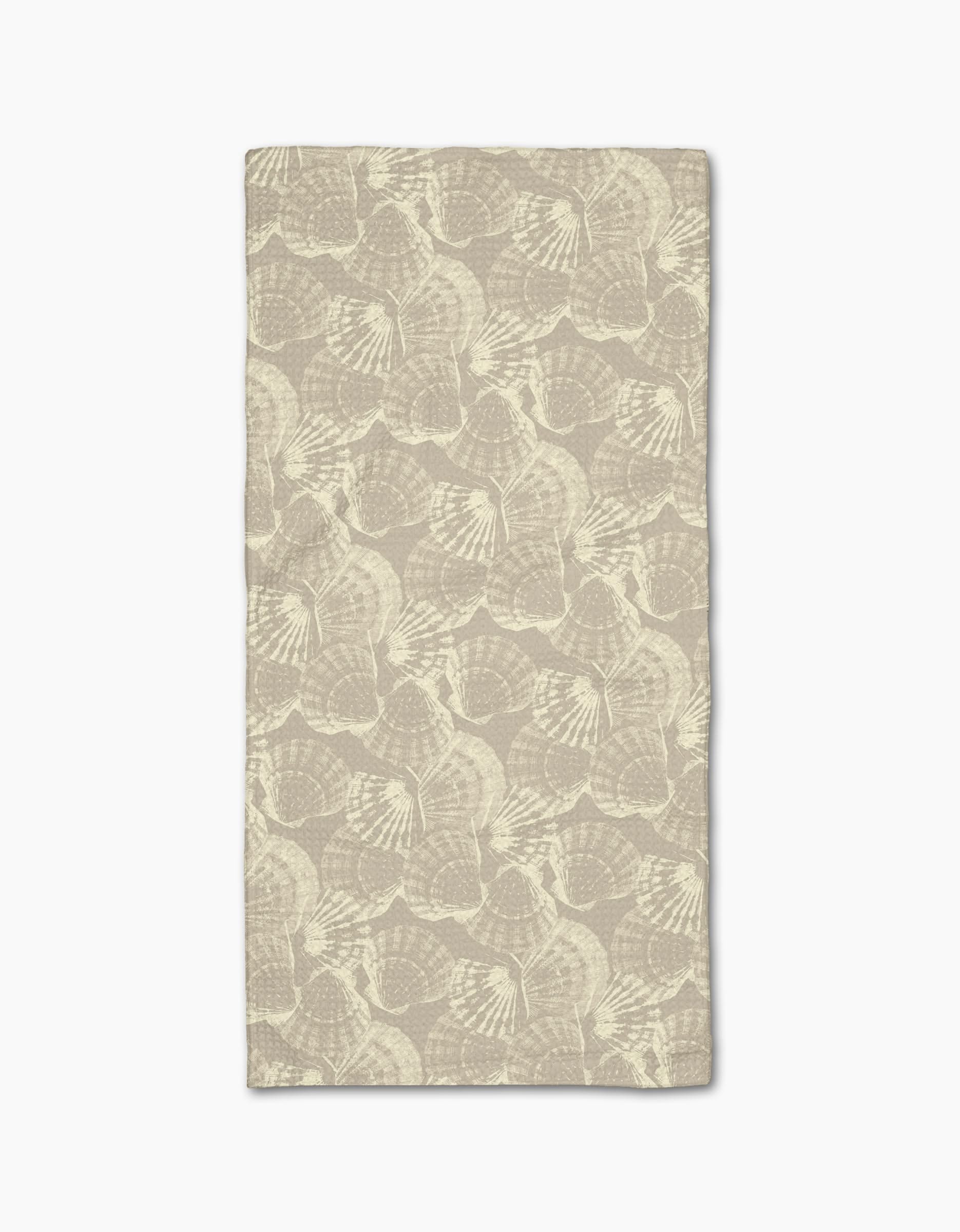 Shell Whisper by Geometry is a rectangular beige cloth napkin, made from post-consumer recycled materials, featuring a subtle, repeating light ginkgo leaf pattern and displayed flat on a white background.