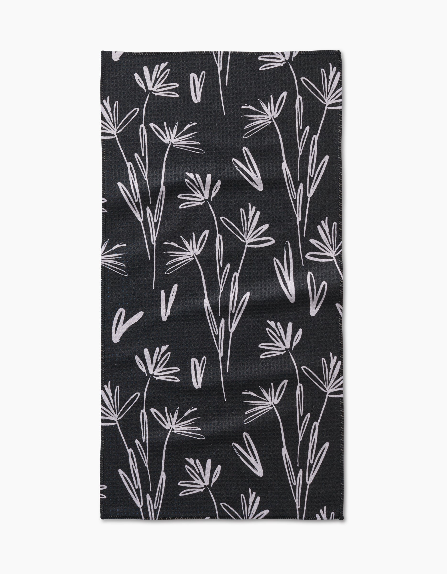 The Toboggan Avenue Sketchbook Dust bar towel is black, rectangular, and made from Geoweave fabric. It features a white minimalist botanical pattern with delicate, abstract flower and leaf outlines across the surface.