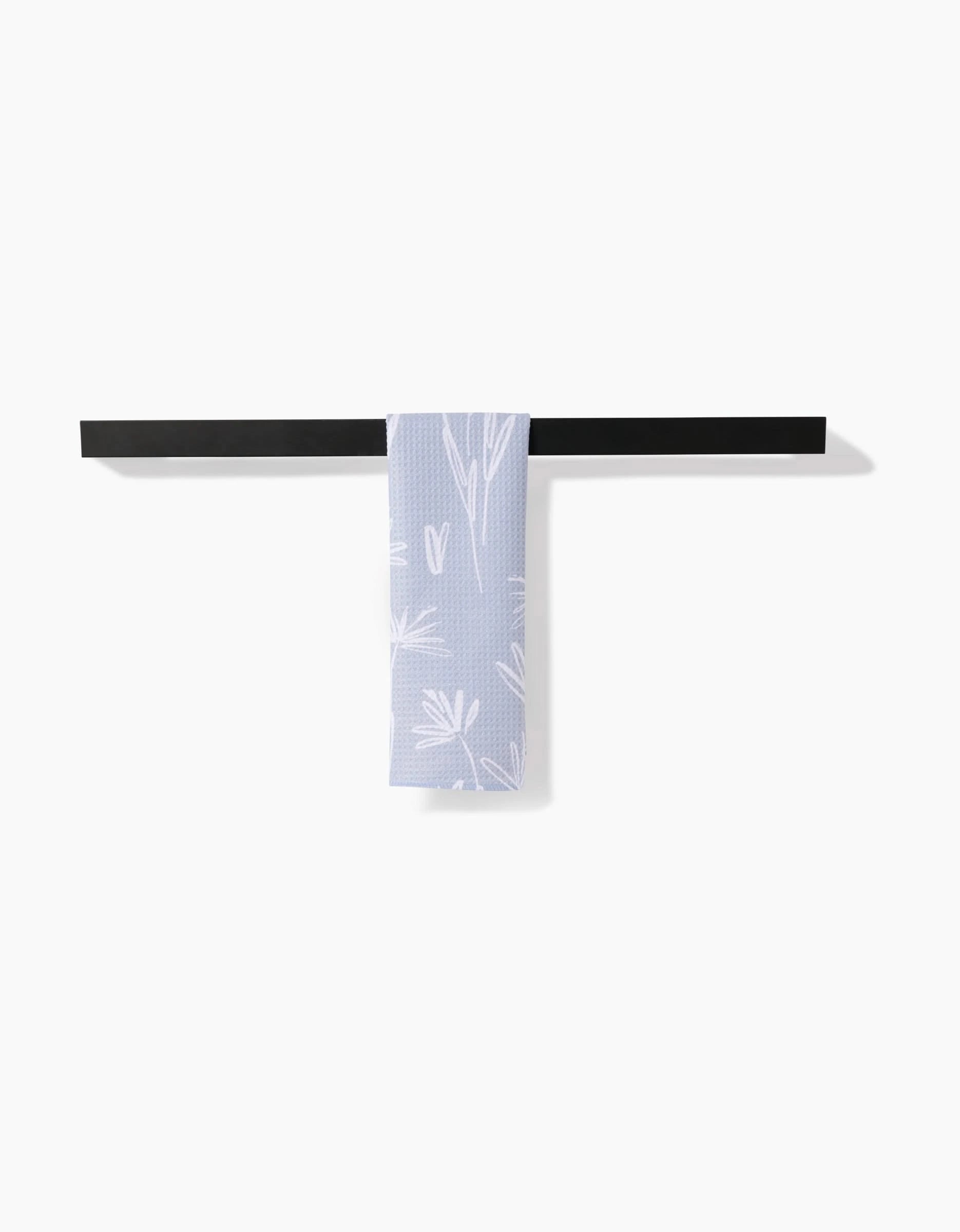 The Toboggan Avenue Sketchbook Floral bar towel, featuring a white botanical pattern on lavender Geoweave fabric, hangs neatly over a horizontal black towel bar against a plain white background.