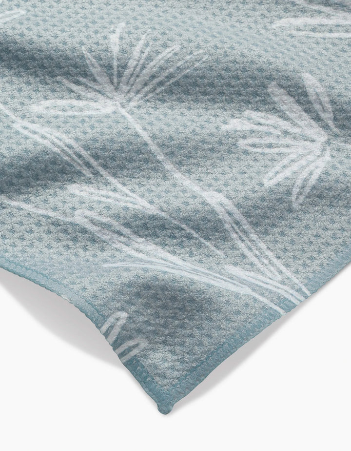 A close-up of Toboggan Avenues Sketchbook Floral Bar Towel in light blue Geoweave fabric, featuring a subtle white botanical pattern and a neatly finished corner.