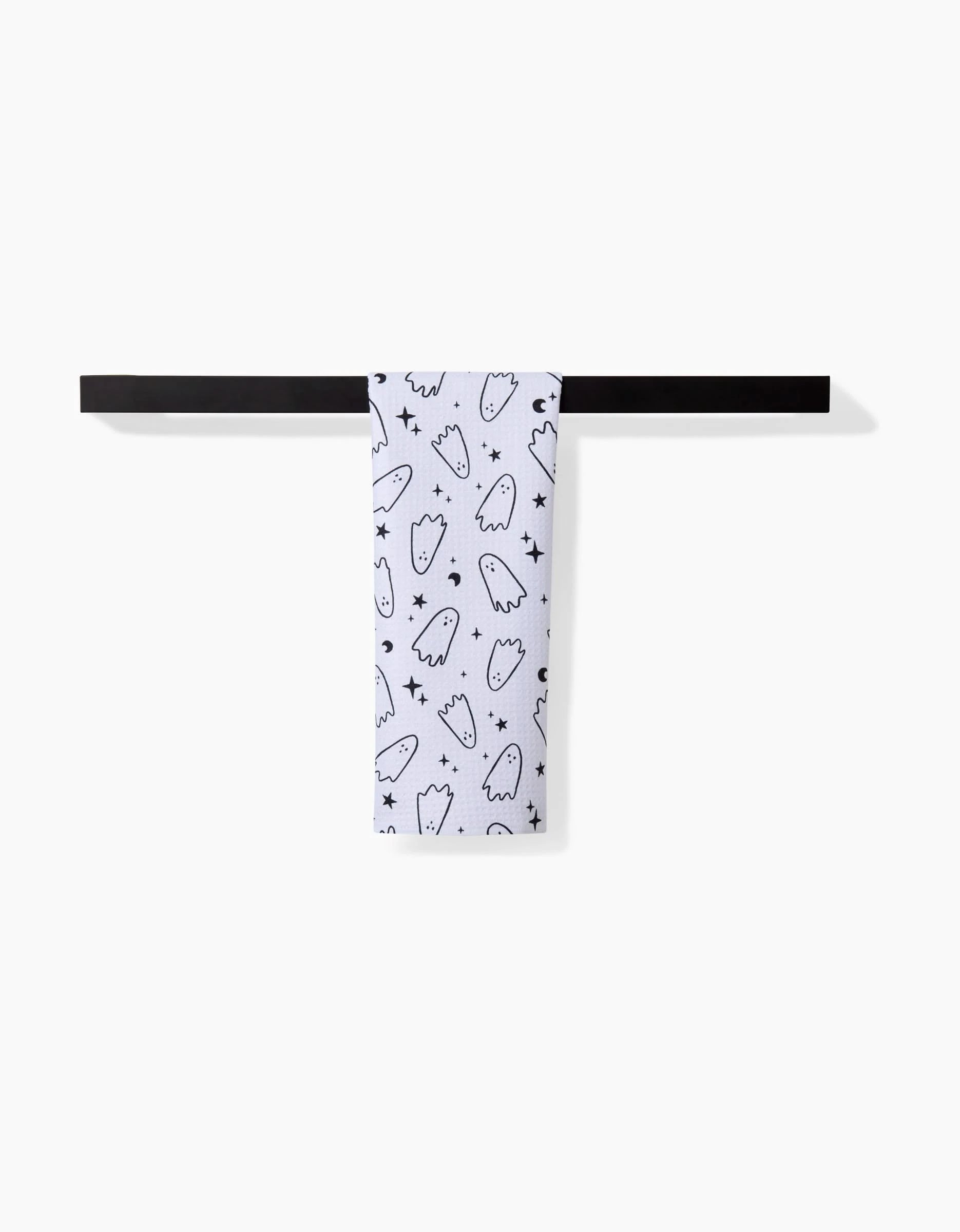 The Space Ghosts Outline towel by Hufton Studio, ultra-absorbent and white with playful black ghost outlines and small stars, hangs neatly on a sleek black bar against a plain white background.