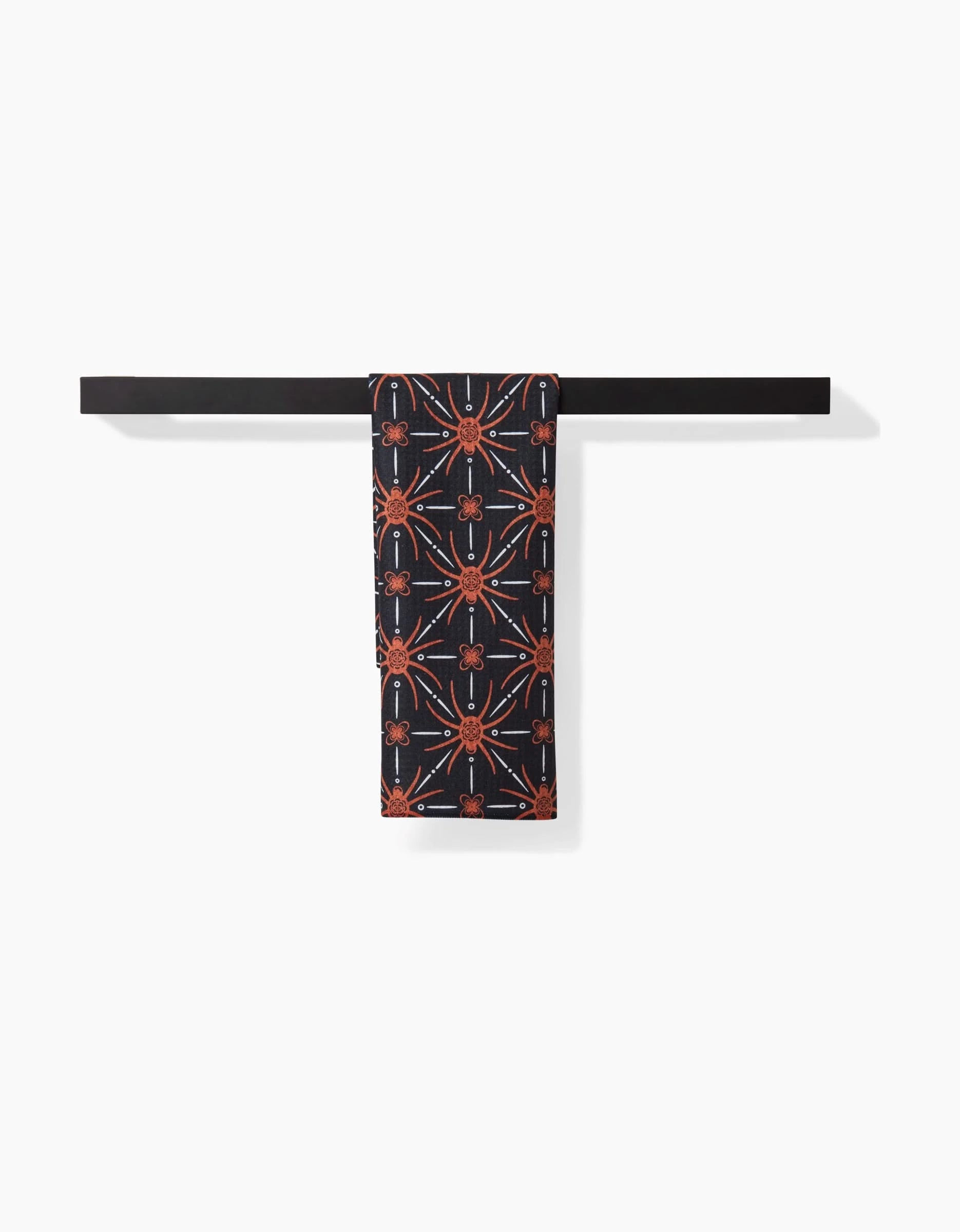 The Spider Geometric scarf by Sarah Daugherty, featuring an orange and white geometric pattern, hangs neatly over a black rod against a plain white background.