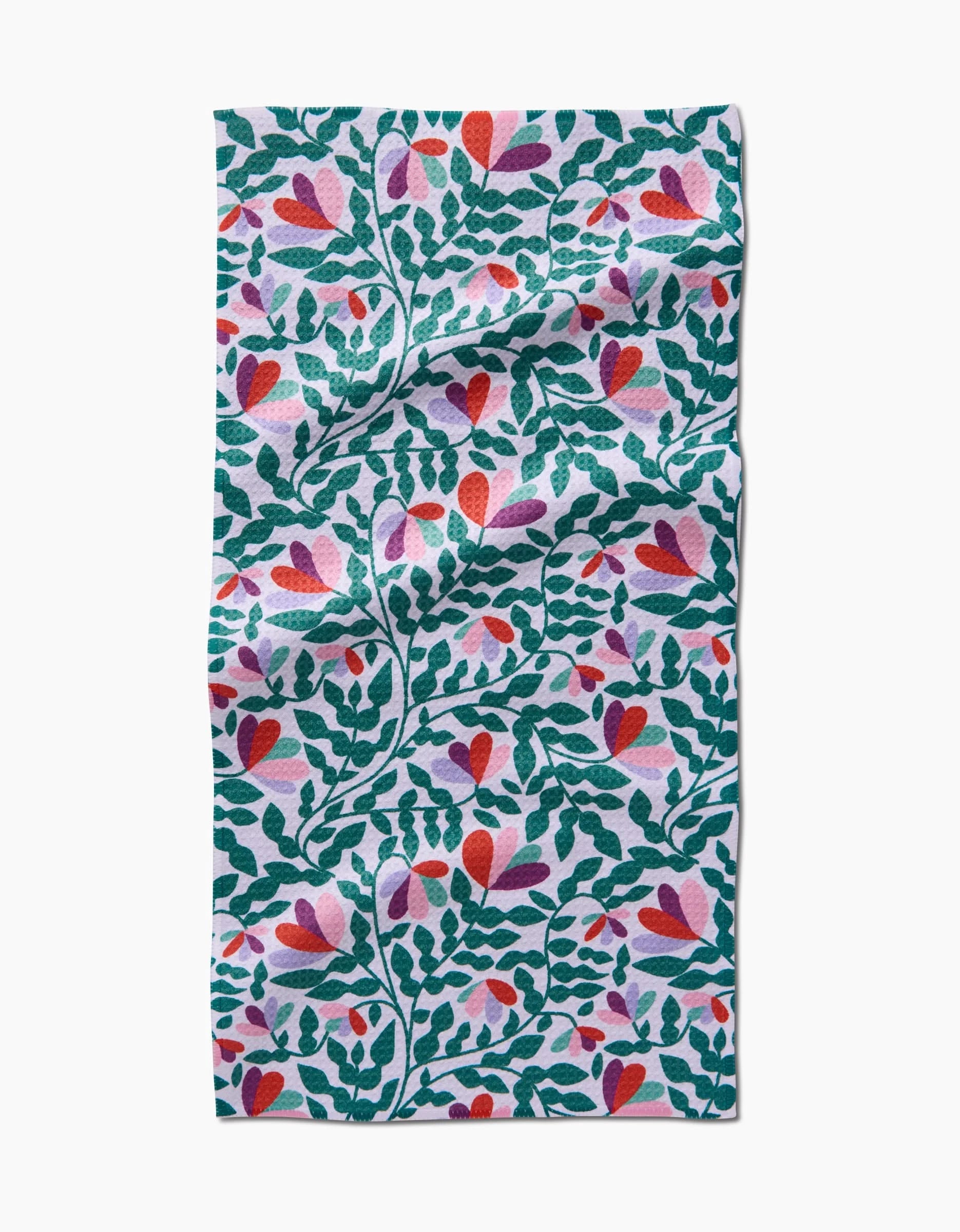 Spring Wavy Leaves by Claire Iglesias is a rectangular bar towel made from recycled materials, featuring a vibrant pattern of green leafy branches, heart-shaped red and pink flowers, and purple accents on white fabric.