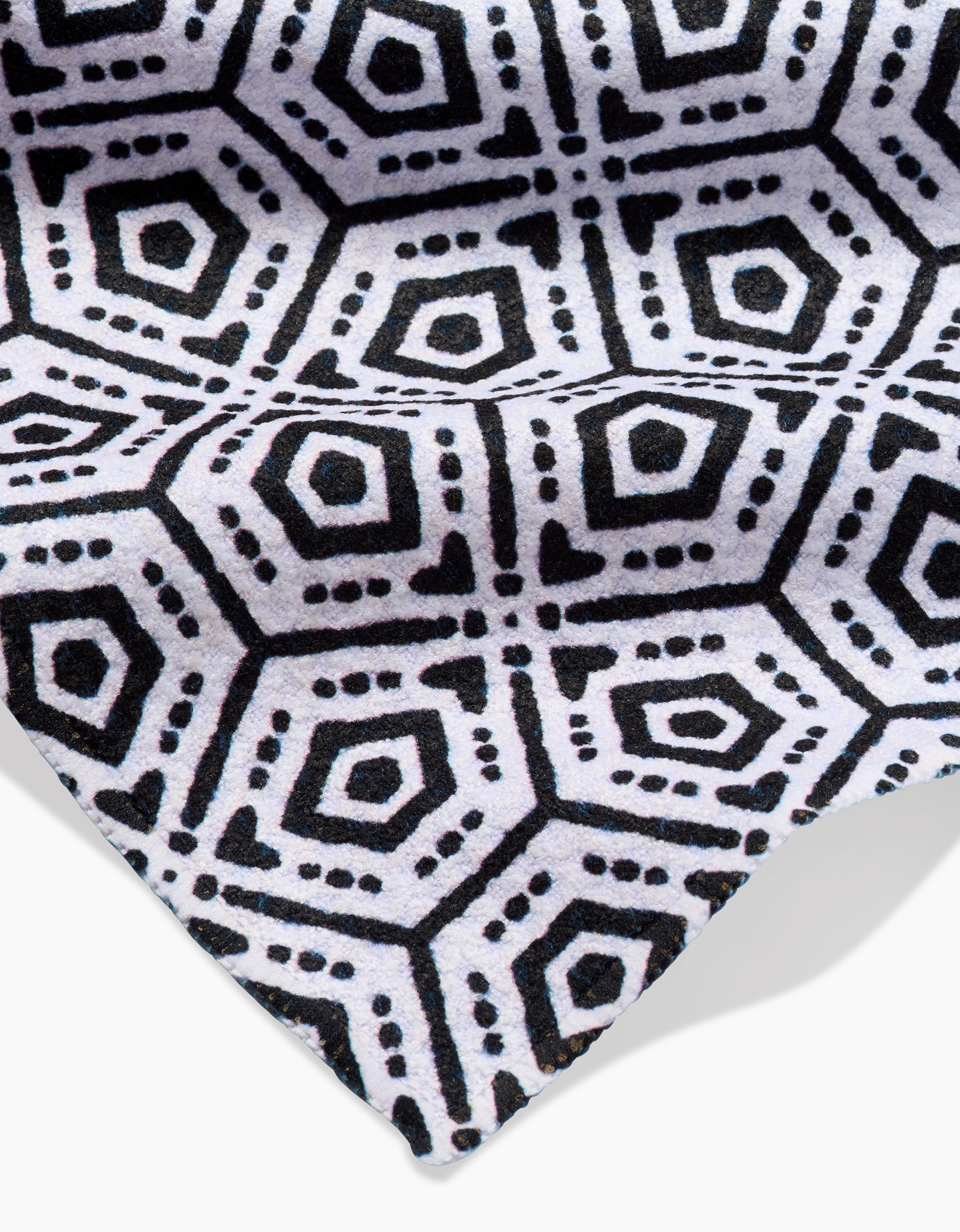 A close-up of Katherine Berkeleys Squeezebox Bar Towel made from recycled materials. The black Geoweave™ fabric features a repeating geometric pattern of hexagons, dots, and hearts on white.