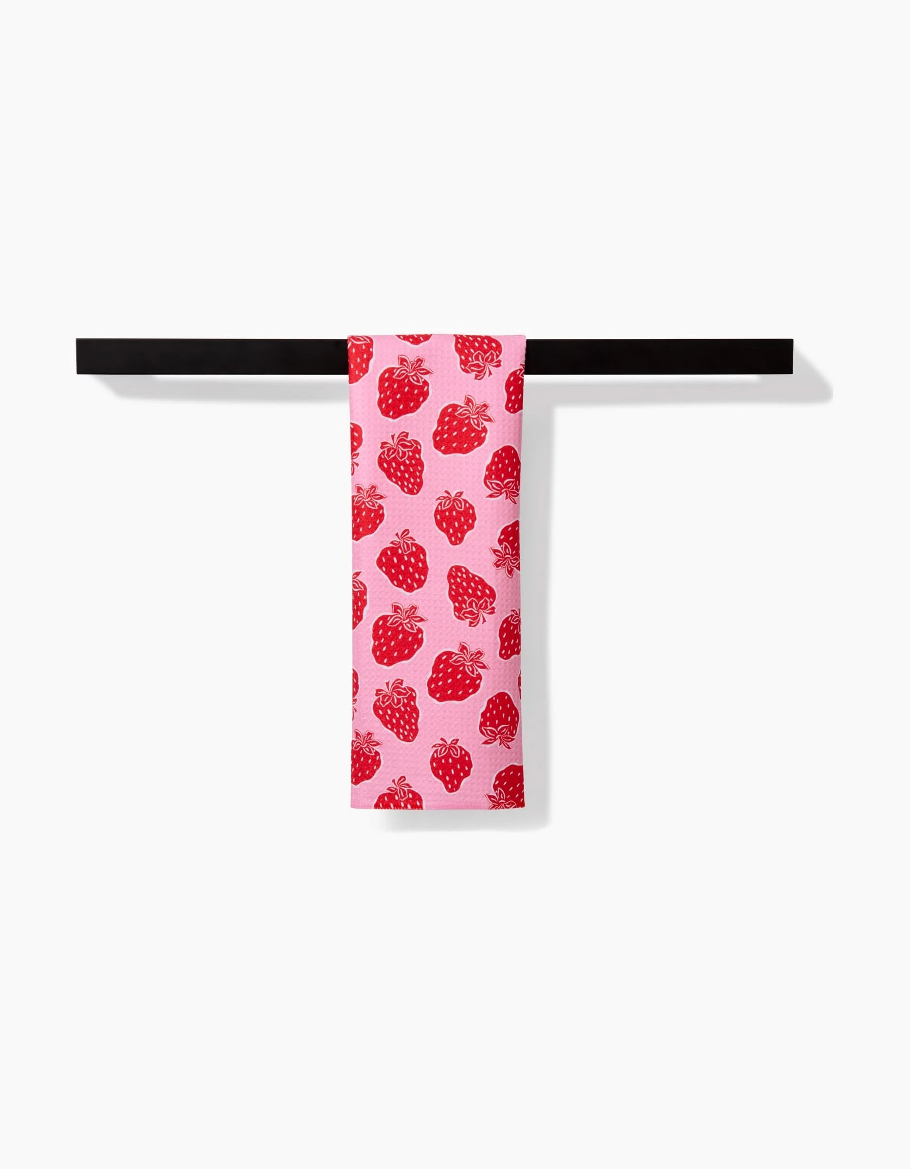 The Strawberry Fields bar towel by Charlie Rowan Designs, crafted from Geoweave fabric, features a red strawberry pattern and hangs neatly on a black bar against a plain white background.