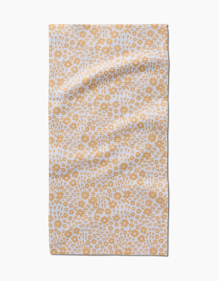 The Summer Fields bar towel by Hufton Studio features a white background with a repeating yellow floral pattern. Made from ultra-absorbent recycled materials, it’s shown laid flat with gentle creases.
