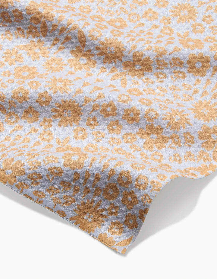 A close-up of the Hufton Studio Summer Fields bar towel, made from ultra-absorbent fabric with a light blue background and an all-over pattern of small brown flowers and leaves. The towel appears slightly wrinkled on a white surface.