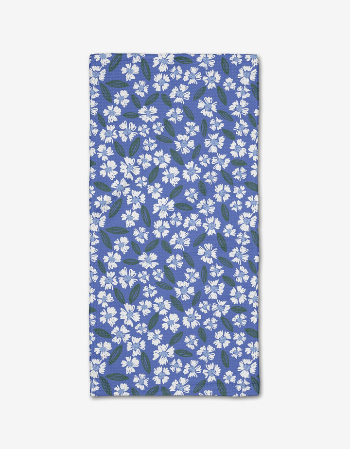 The Hufton Studio Sweetie Floral bar towel, made from eco-friendly Geoweave fabric, features a rectangular blue design with small white flowers and green leaves, shown flat on a white background.