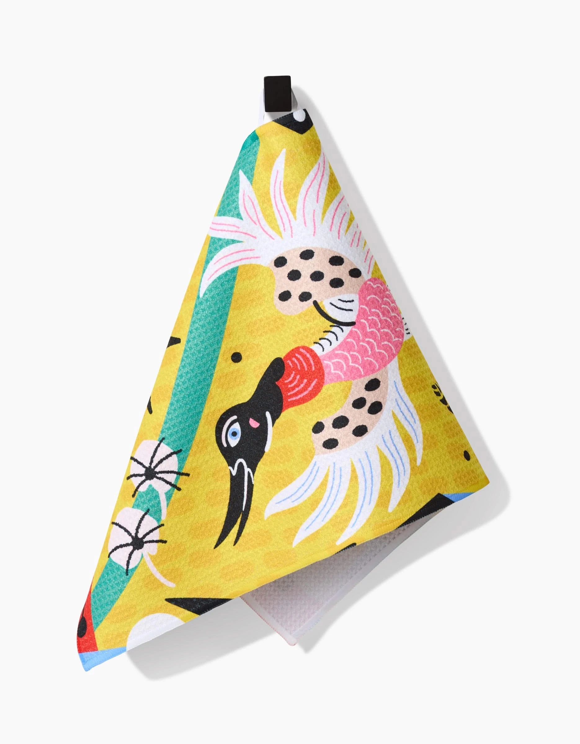 The Tuiuiú Bar Towel by Camila Leão showcases a stylized crane with black, white, and pink feathers on a yellow background with floral graphics. Made from ultra-absorbent Geoweave fabric, it features a handy black hanging loop.