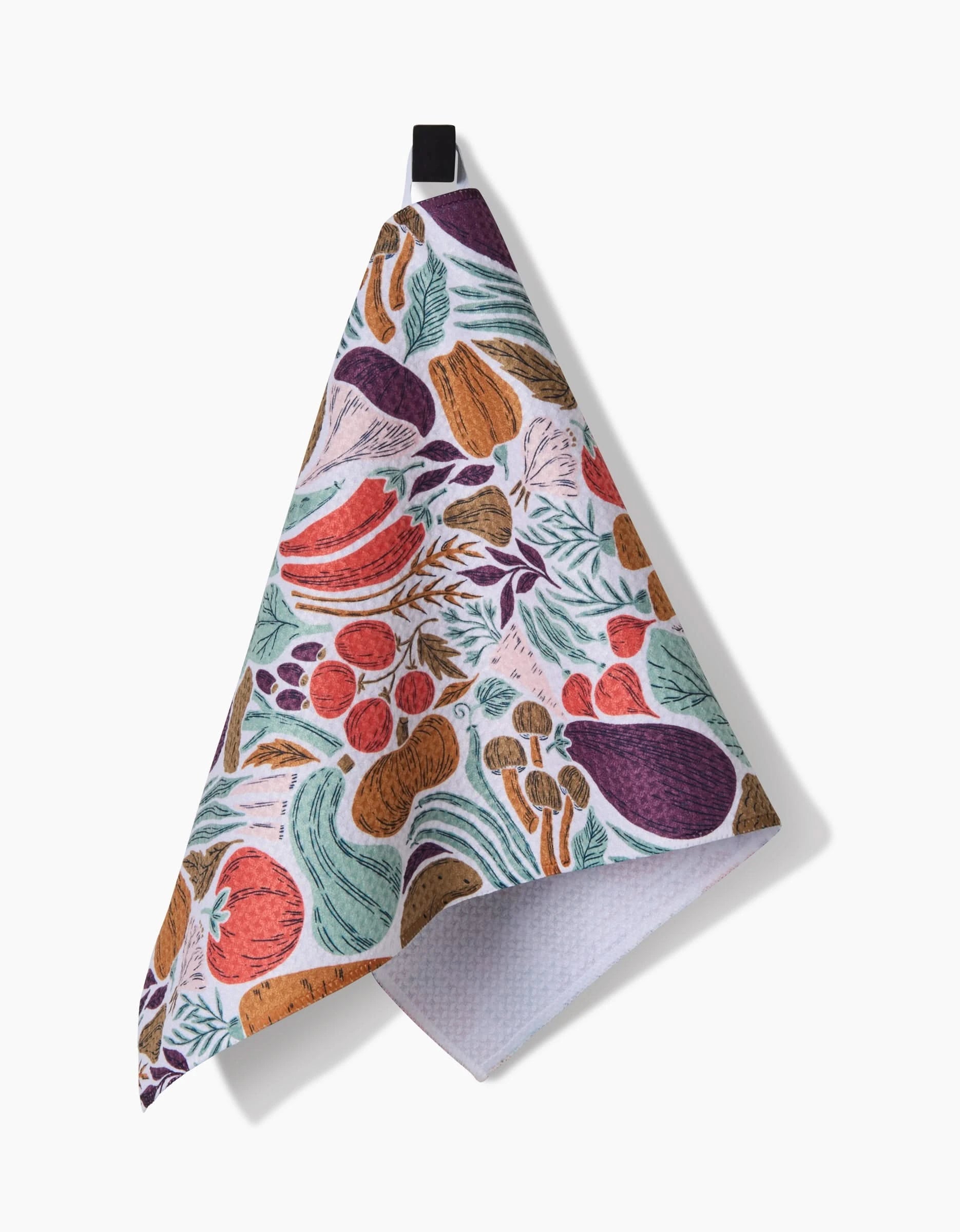 Twila by Amy MacCready is a vibrant kitchen bar towel crafted from recycled materials, featuring tomato, eggplant, carrot, and herb illustrations. It hangs from a black loop on a white background.