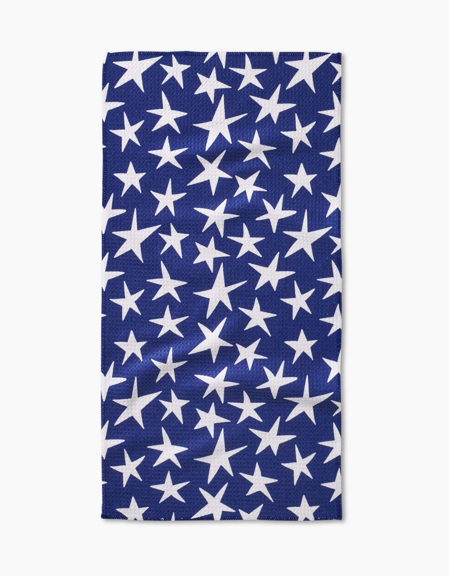 The Mindfulnice USA Stars Bar Towel, made from Geoweave fabric, displays white stars of assorted sizes on a dark blue background and is shown flat on a white surface.