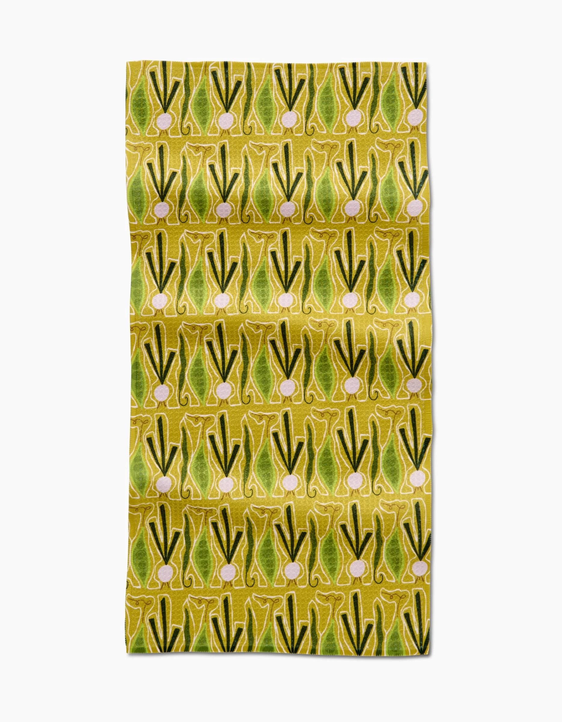 The Lizzie Clark Veg on Parade bar towel features a repeating pattern of green and yellow stylized leeks or onions with pinkish bulbs on a yellow background. Made from slightly wrinkled Geoweave fabric crafted from recycled materials.