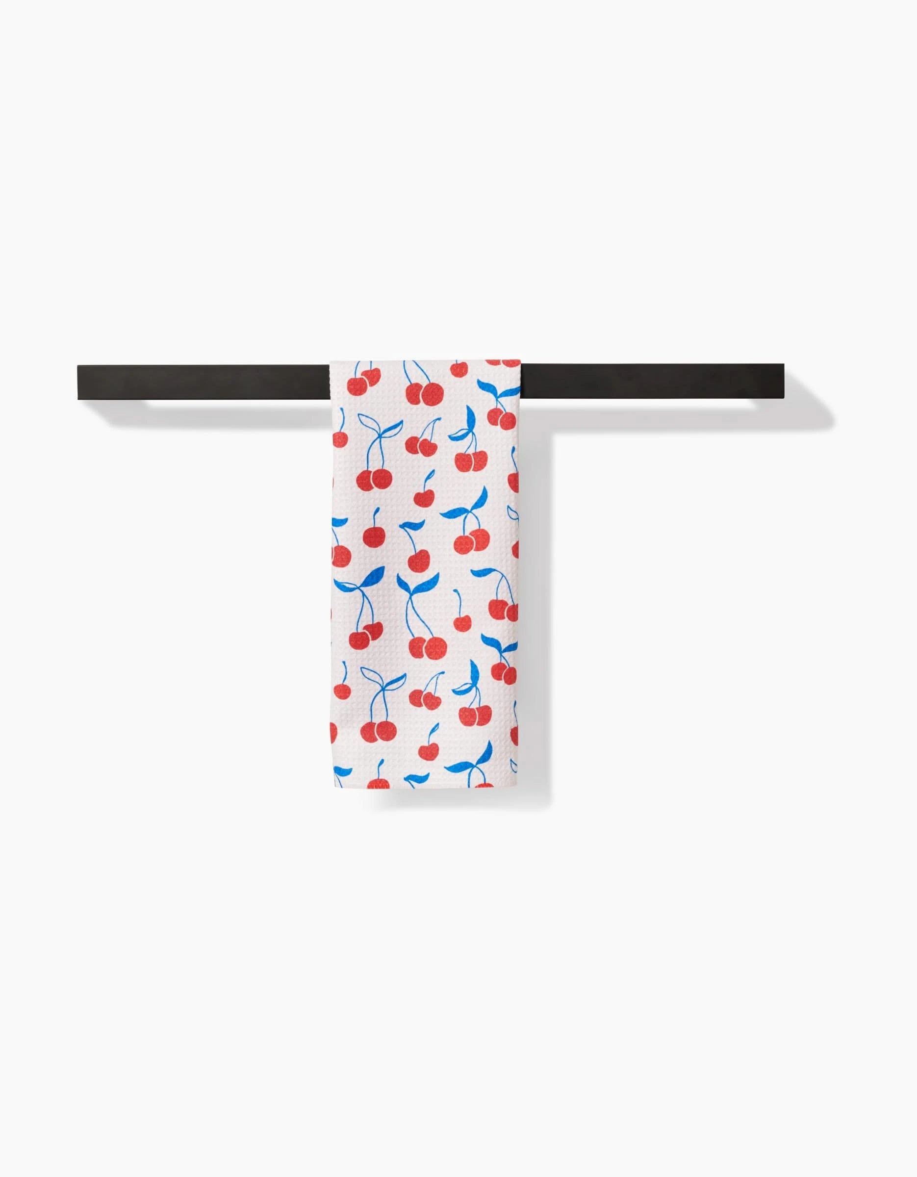 The Kayla Ann Very Cherry Bar Towel, crafted from premium Geoweave fabric, showcases a red cherry and blue stem design and hangs neatly on a horizontal black bar against a plain white background.