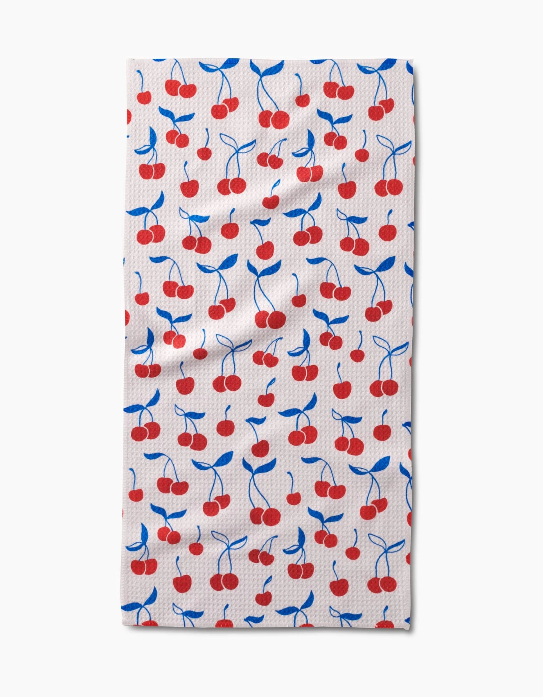 The Kayla Ann Very Cherry Bar Towel is rectangular and white, featuring red cherries with blue stems and leaves on Geoweave fabric for extra absorbency and durability.