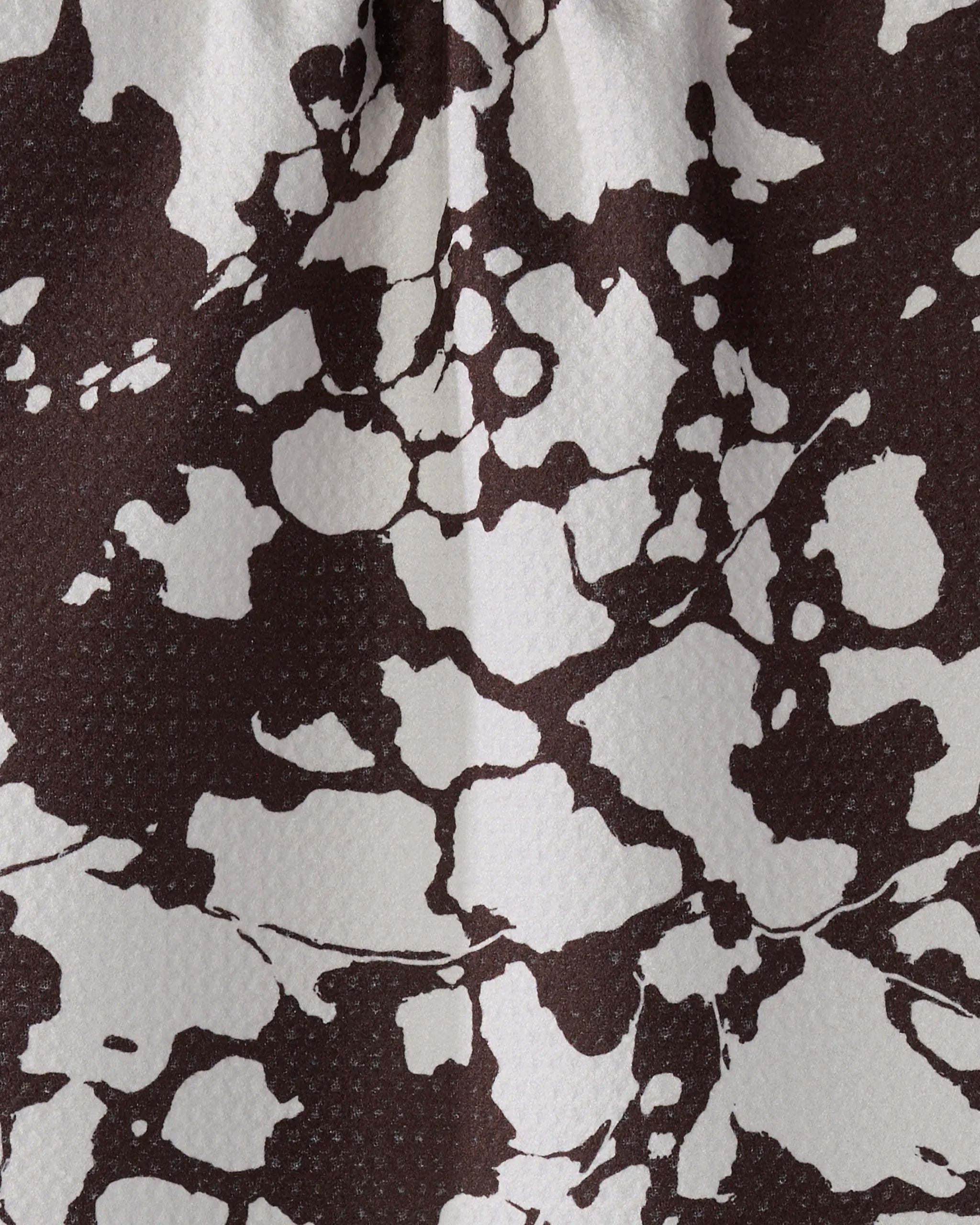 Close-up of Vine Noir by Geometry—a textured surface with an abstract black and white marbled pattern, crafted from recycled materials.