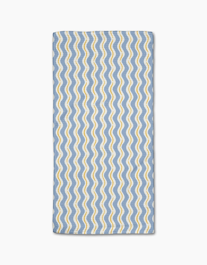 The Wave Ripple Stripes bar towel by Hufton Studio features a rectangular blue Geoweave fabric with wavy yellow and white parallel lines in a repeating pattern, neatly folded and displayed on a white background.