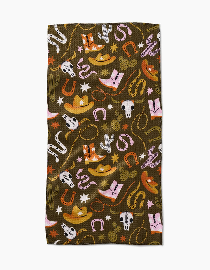 The Wild Cowboy bar towel by Megan Roy features a western pattern with cowboy hats, cacti, boots, and more in vibrant colors—crafted from recycled materials for an eco-friendly touch.