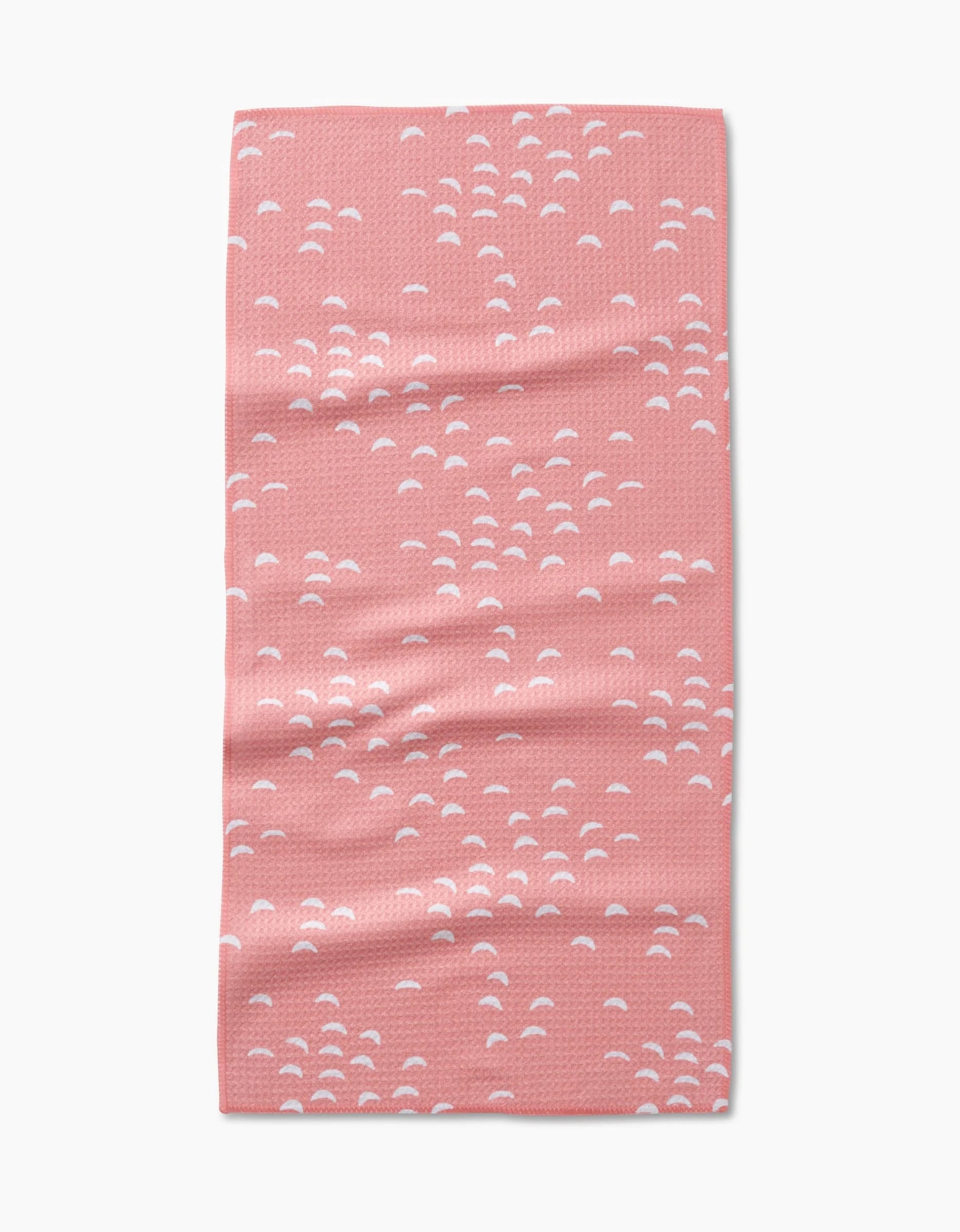 The “Windswept” bar towel by Jessica Swift is pink, rectangular, and made from Geoweave fabric. It features a scattered small white semi-circle pattern and is shown flat on a white background.