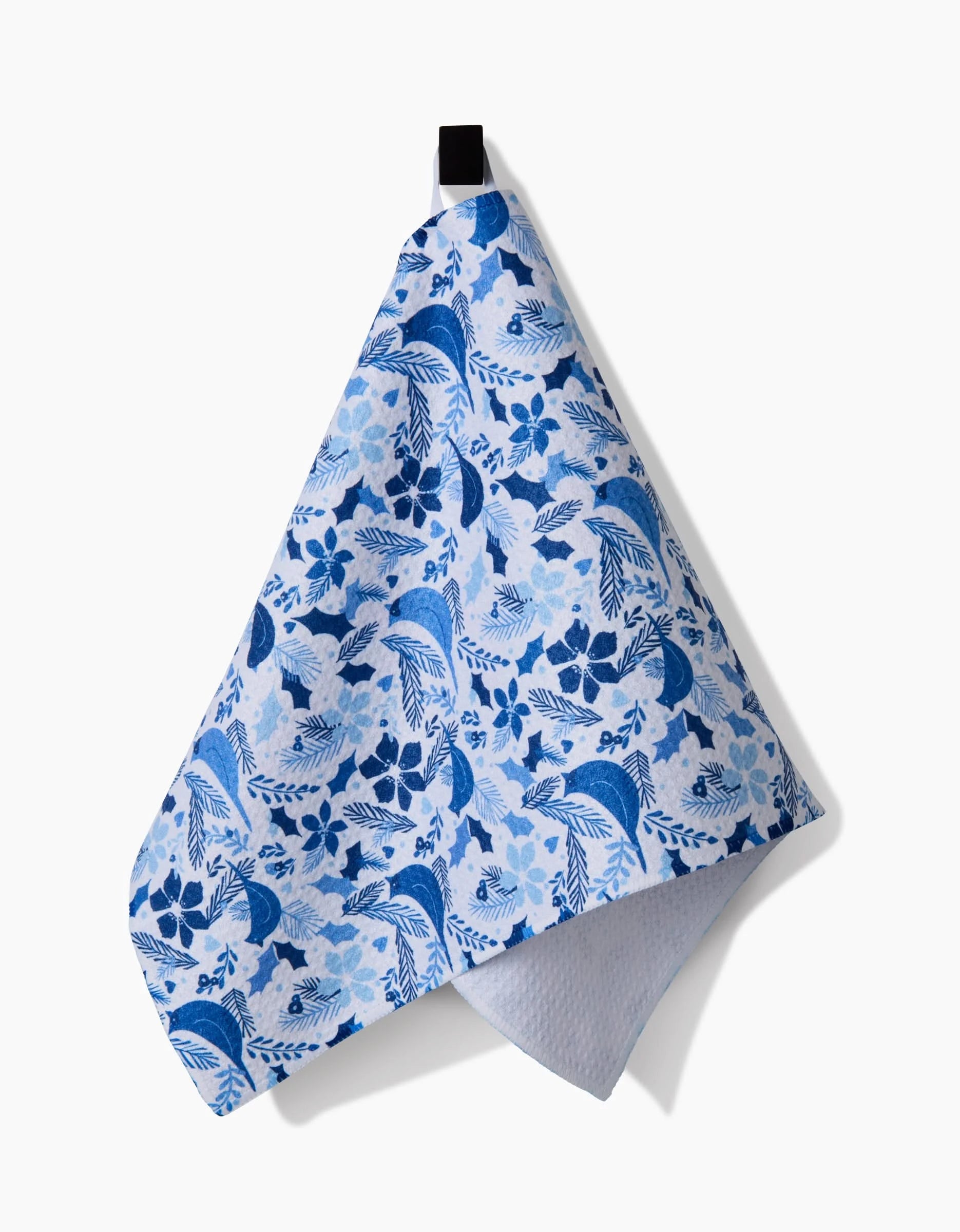 The Kris Ruff Winter Blue Birds towel, featuring a blue and white floral pattern, hangs from a black loop against a plain white background.