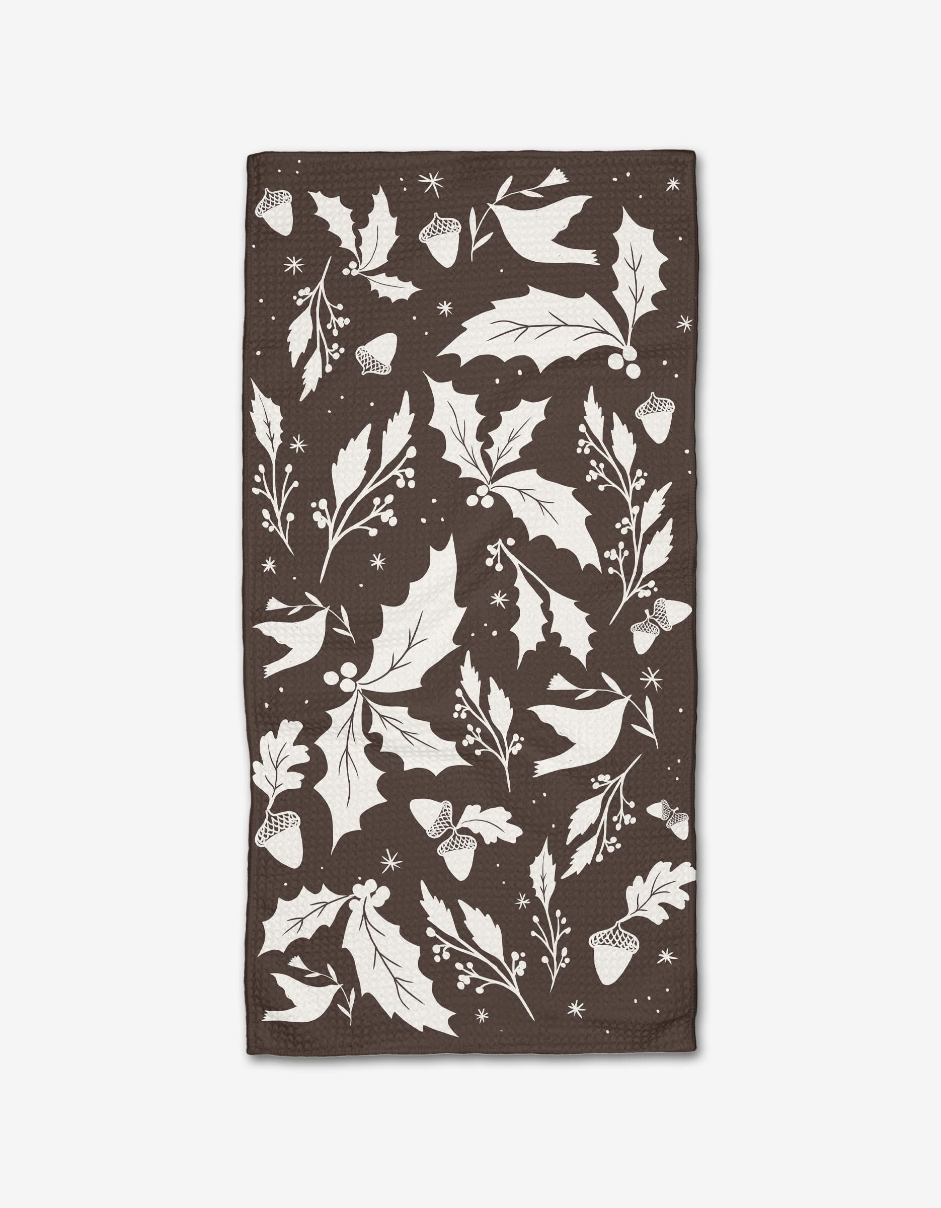 The Elana Gabrielle Winter Forest Floor Bar Towel is a dark brown rectangular towel made from Geoweave fabric, featuring a white botanical pattern with holly leaves, berries, acorns, and snowflakes.