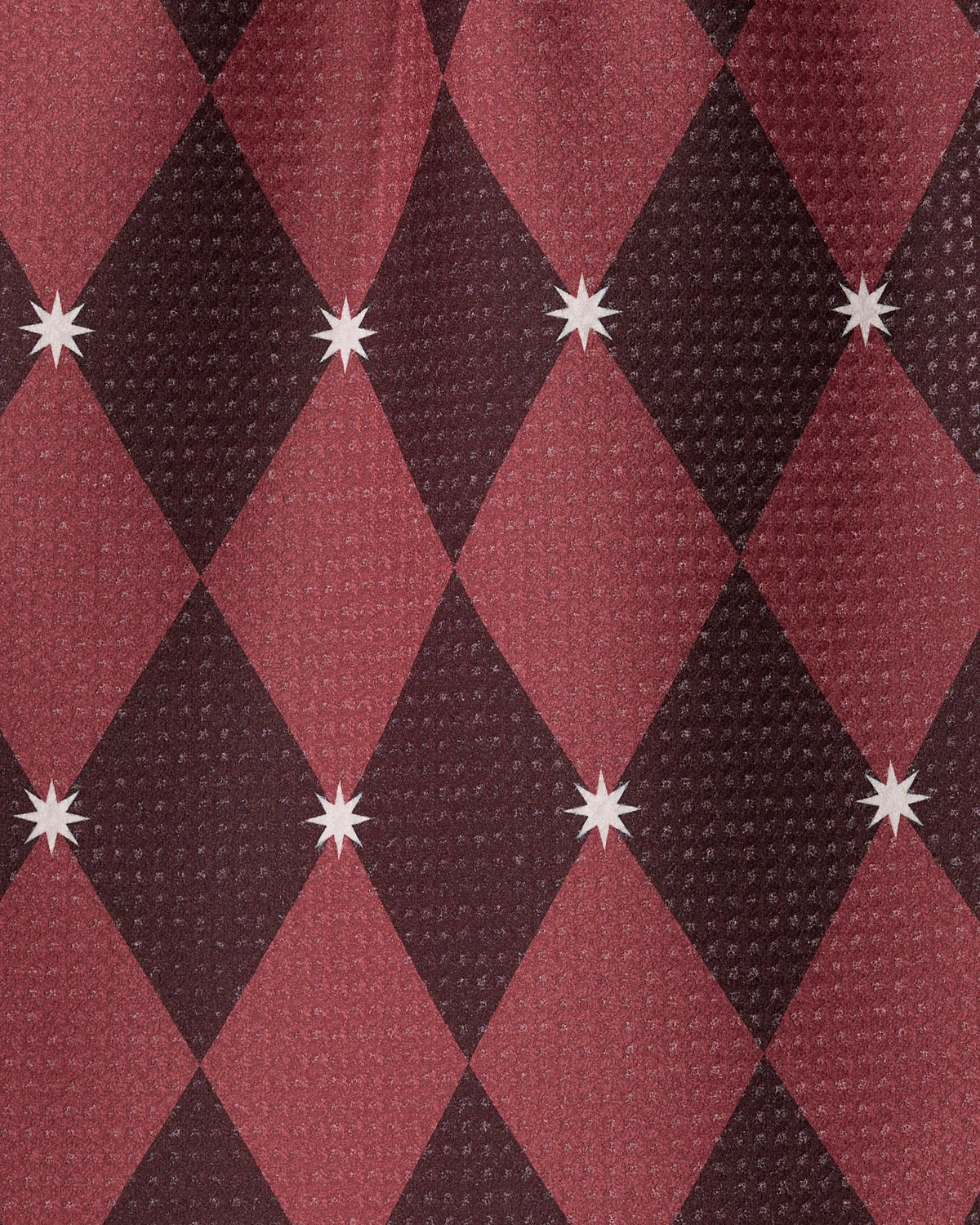Winter Gems by Geometry features a red and black diamond pattern accented with white eight-pointed stars at the intersections, all displayed on a textured, waffle-like Geoweave fabric background crafted from recycled materials.