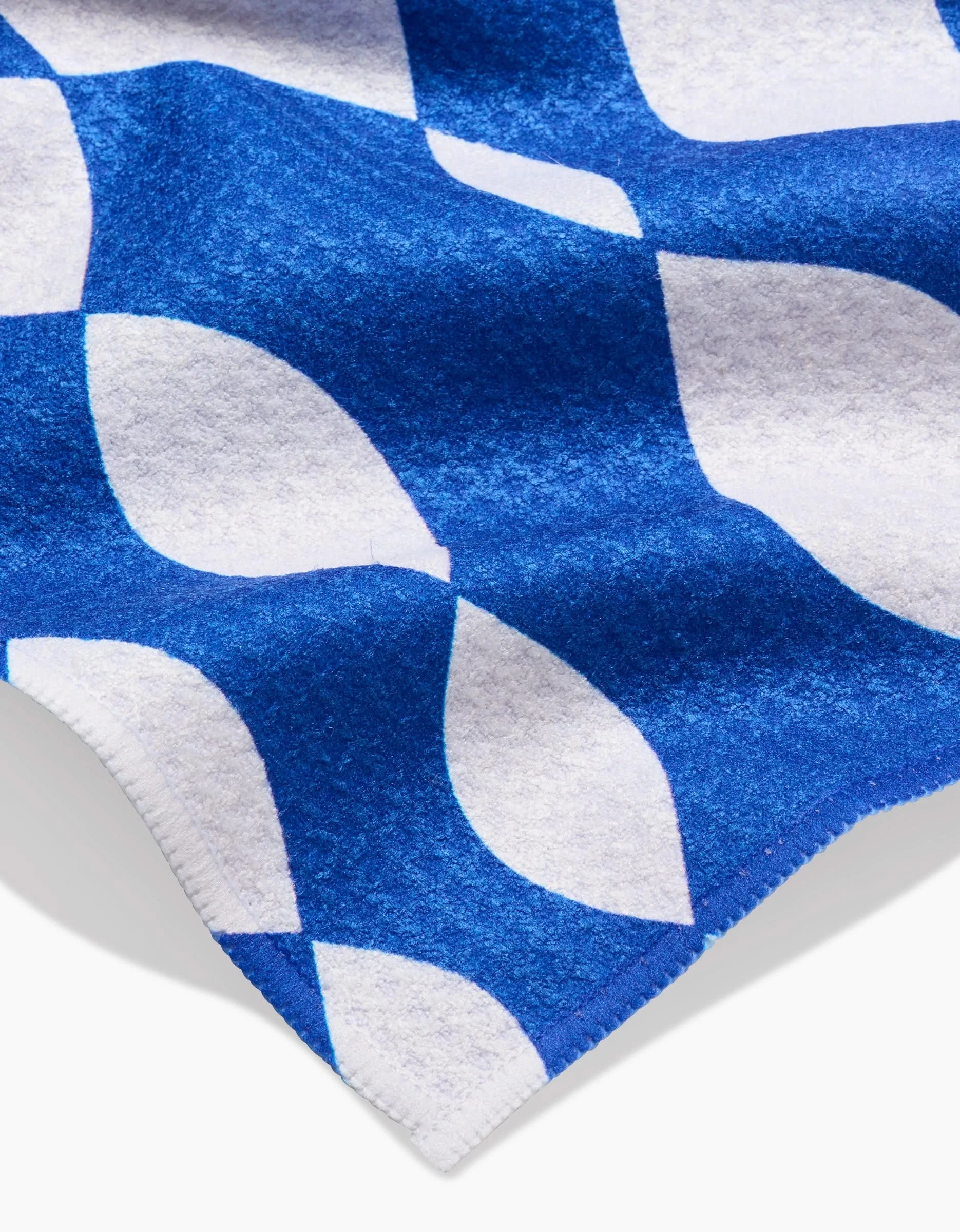 A close-up of the Claire Iglesias Wonky Lines bar towel, featuring a blue and white Geoweave fabric with interlocking geometric shapes, neat stitching, a soft finish with slight sheen, and possibly made from recycled materials.