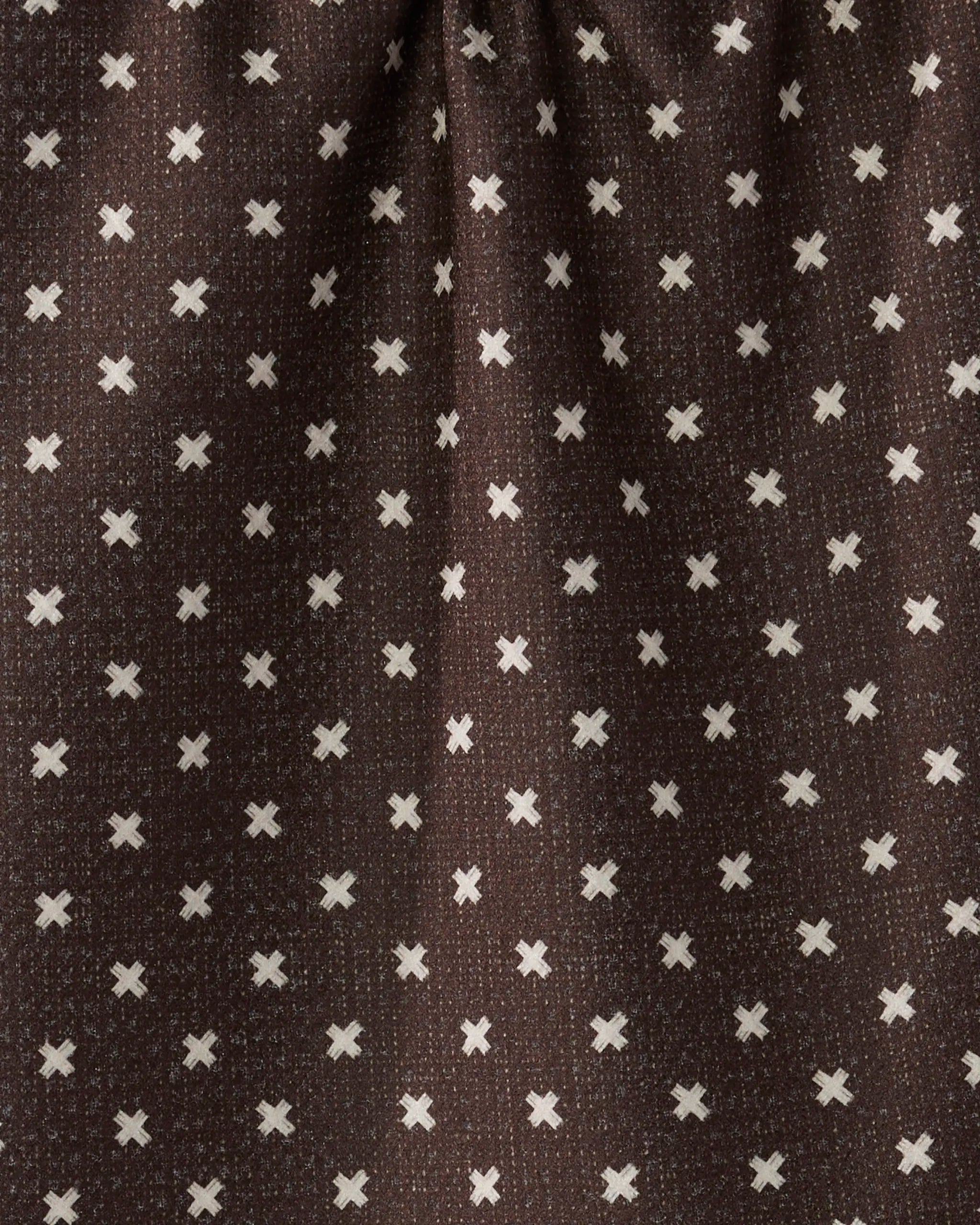 Woven Spice by Geometry features dark brown fabric with evenly spaced small white X patterns. Made from recycled materials, this bar towel is slightly gathered at the top for a stylish, eco-friendly touch.