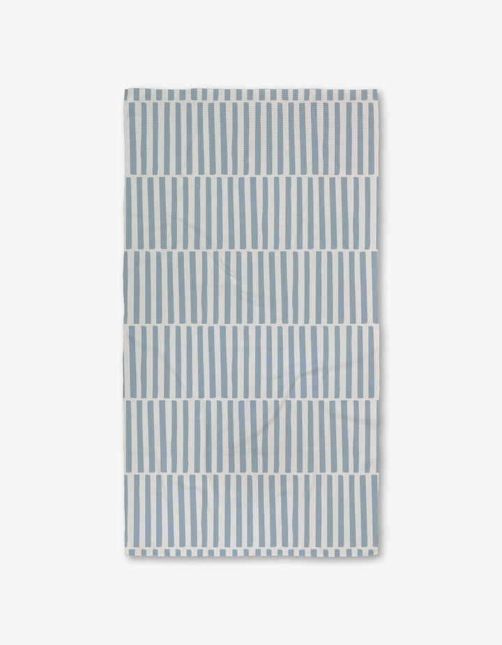 The Aubrey Fairchild Blue Stripes Luxe Bath Towel features ultra-absorbent Geoweave technology and a pattern of vertical blue stripes with white spaces, displayed on a white background.