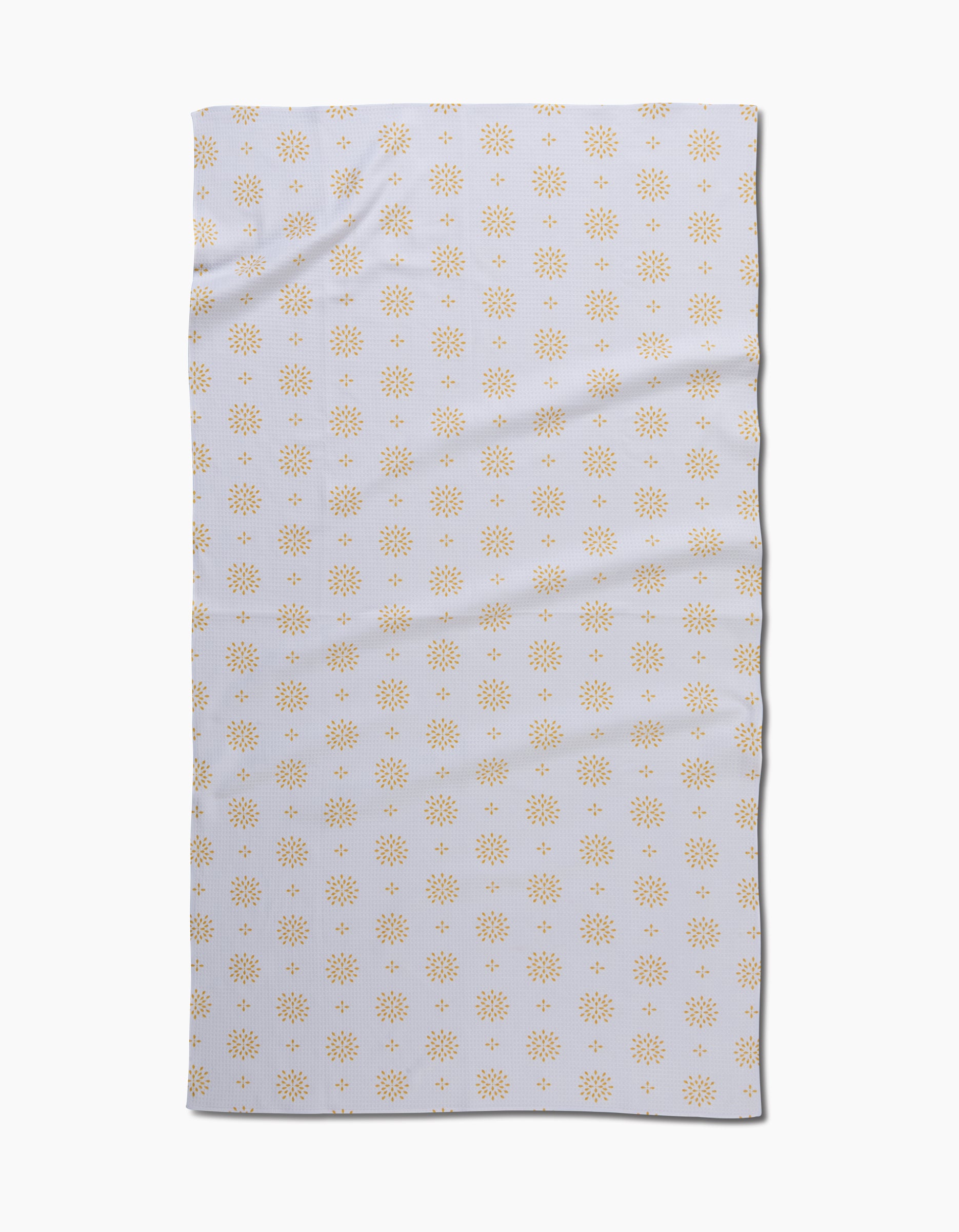 The Danelys Sidron Morning Petals bath towel is rectangular and white, featuring a repeating pattern of small yellow sunbursts. Slightly wrinkled, the towel is displayed on a plain white background.