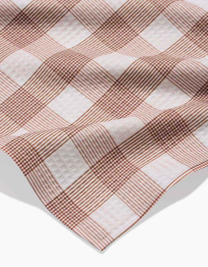 A close-up of Hufton Studio’s Vintage Gingham Natural bath towel, showing its red and white checkered pattern with large squares and textured thin and thick lines, slightly wrinkled against a white background.