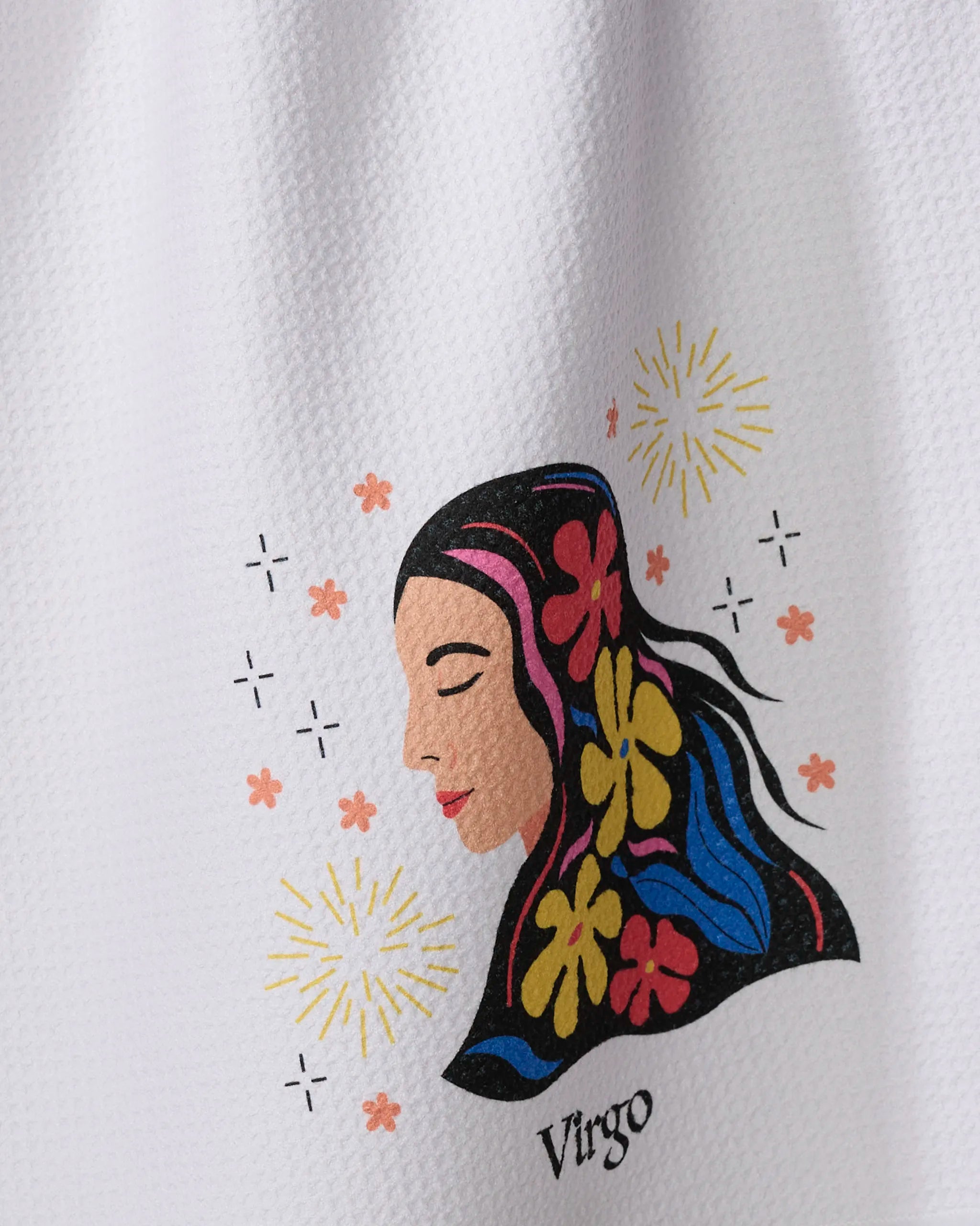 The "Clever Virgo" kitchen towel by Heather Zhou features a woman's side profile with closed eyes, colorful flowers in her hair, and fireworks. The word Virgo appears below on white textured recycled material.