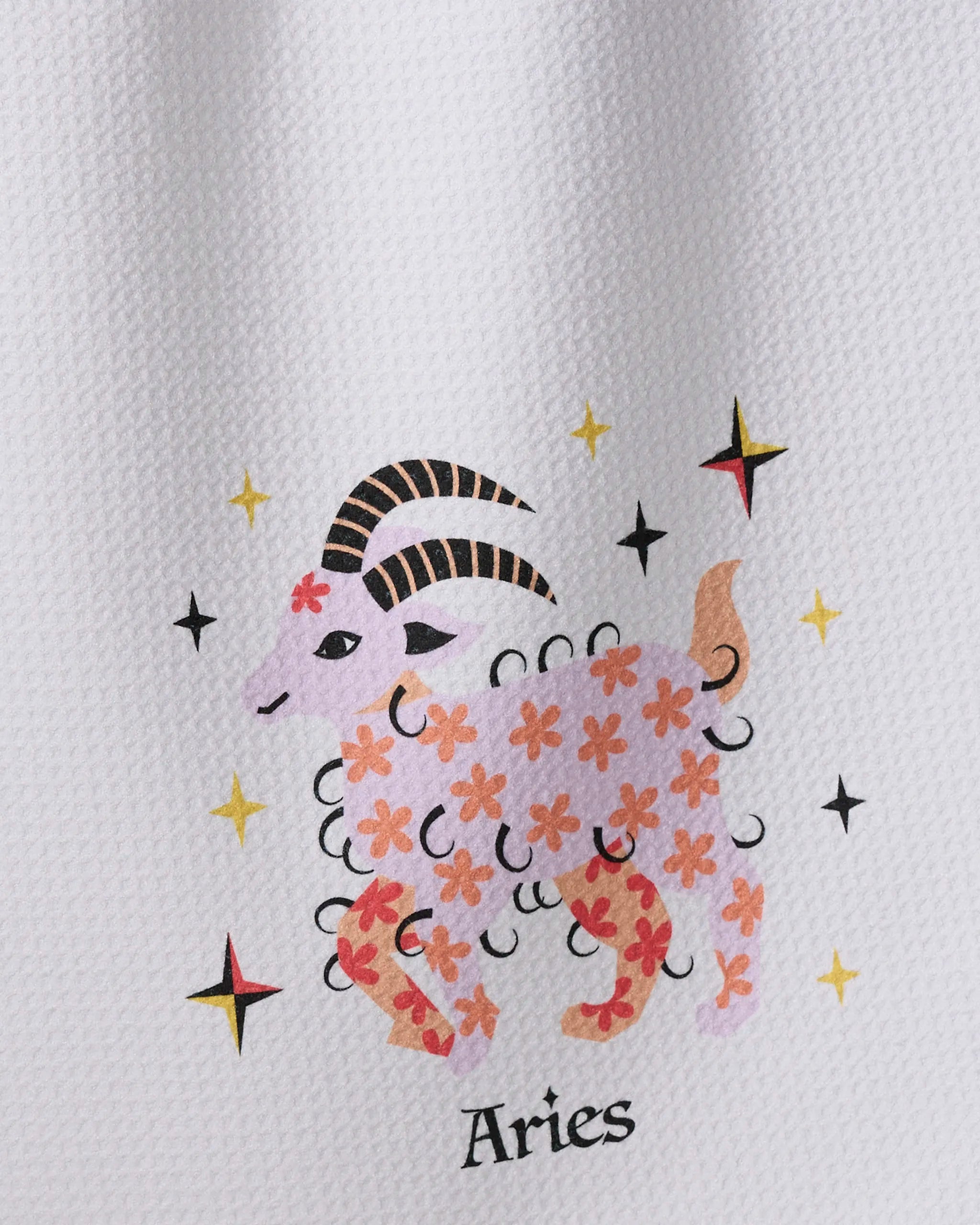 The Daring Aries towel by Heather Zhou features a ram with pink floral patterns, black curved horns, and yellow and black stars, with "Aries" inscribed below on an ultra-absorbent textured background.