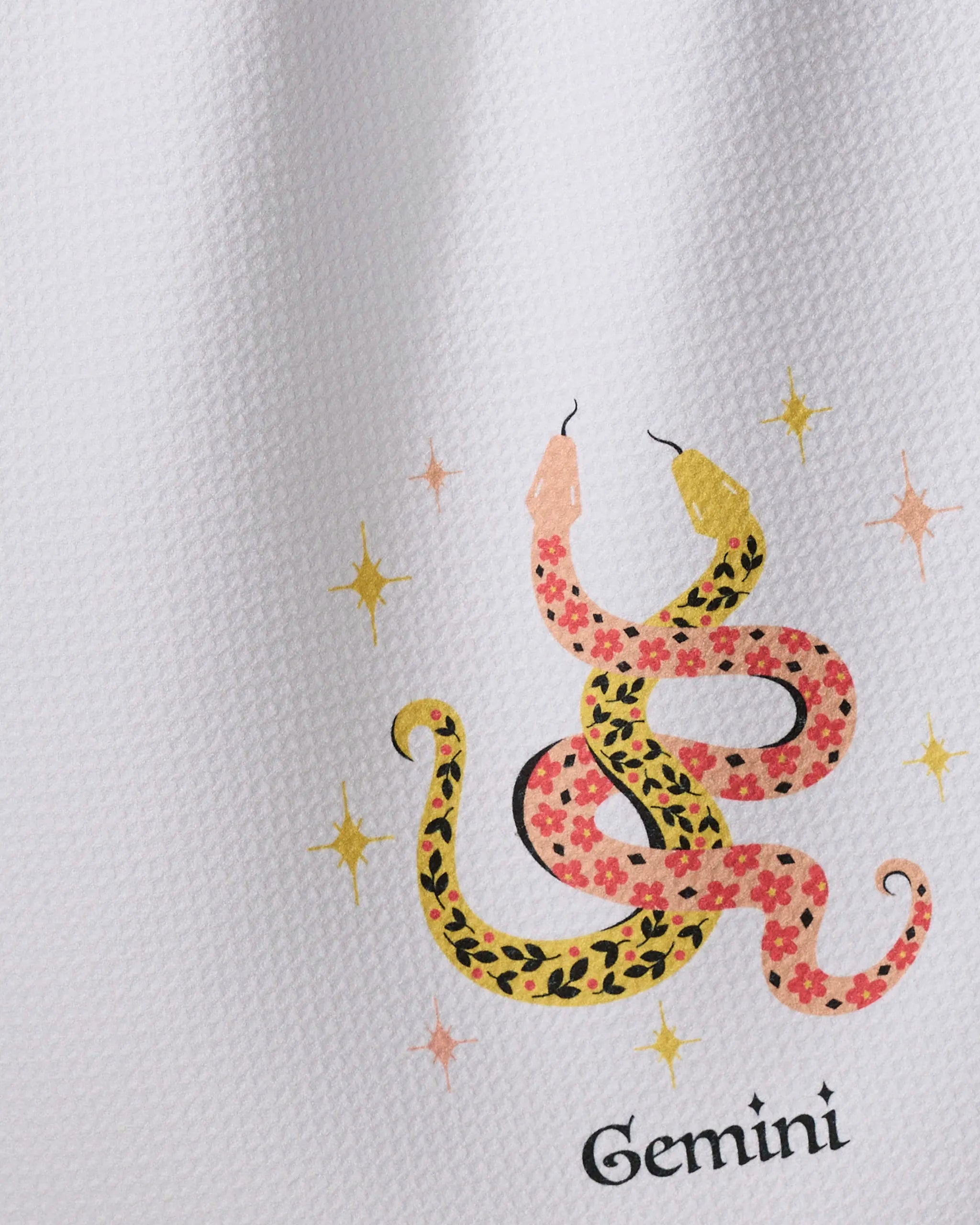 Lucky Gemini by Heather Zhou: a tea towel made from recycled materials, featuring a stylized two-headed floral snake, yellow stars, and 'Gemini' text on a textured white background.
