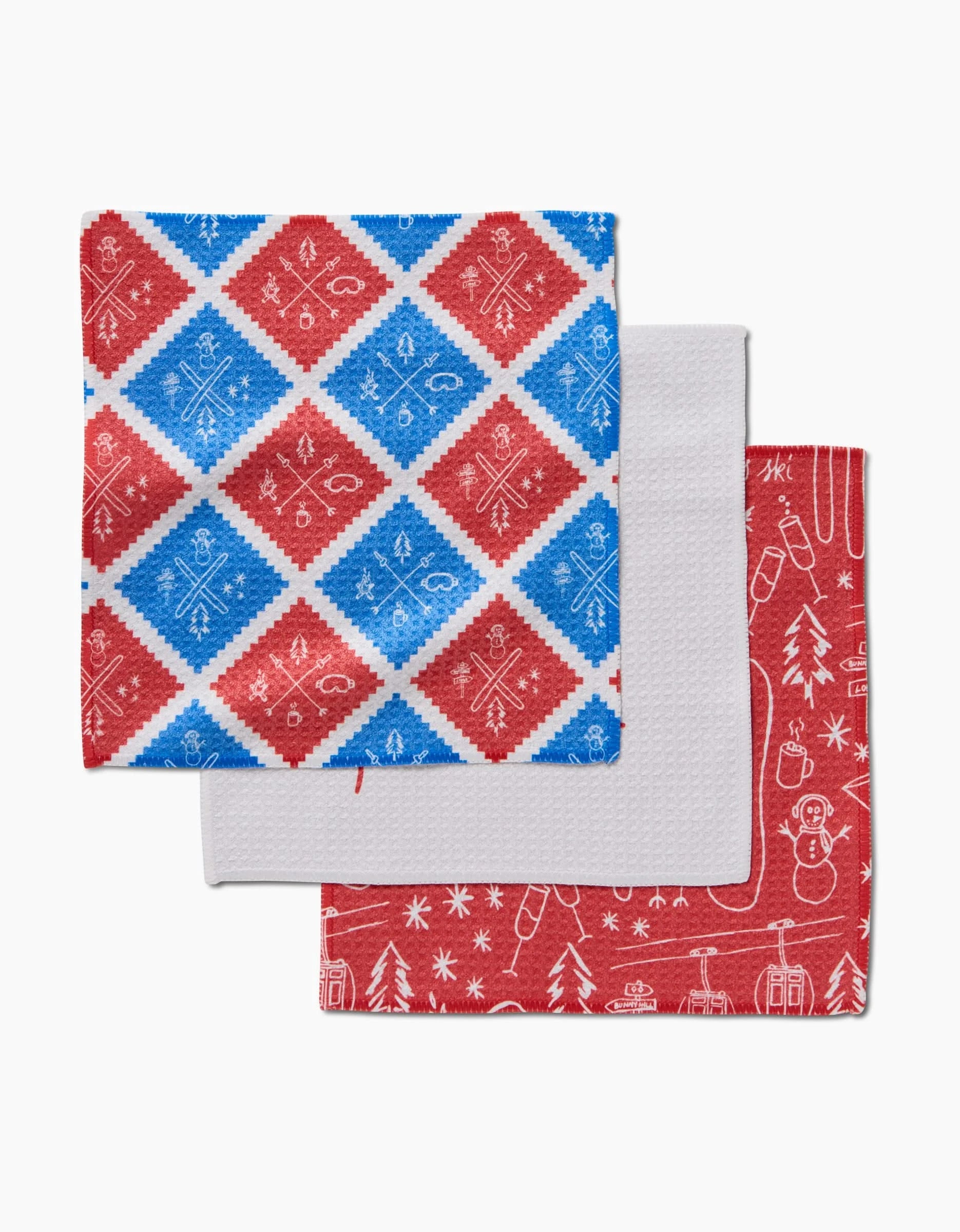 The Rosa Kichline Apres Ski set includes three folded kitchen tea towels: one with blue and red snowflake diamonds, one plain white, and one red with white winter holiday illustrations—perfect for festive dishwashing.