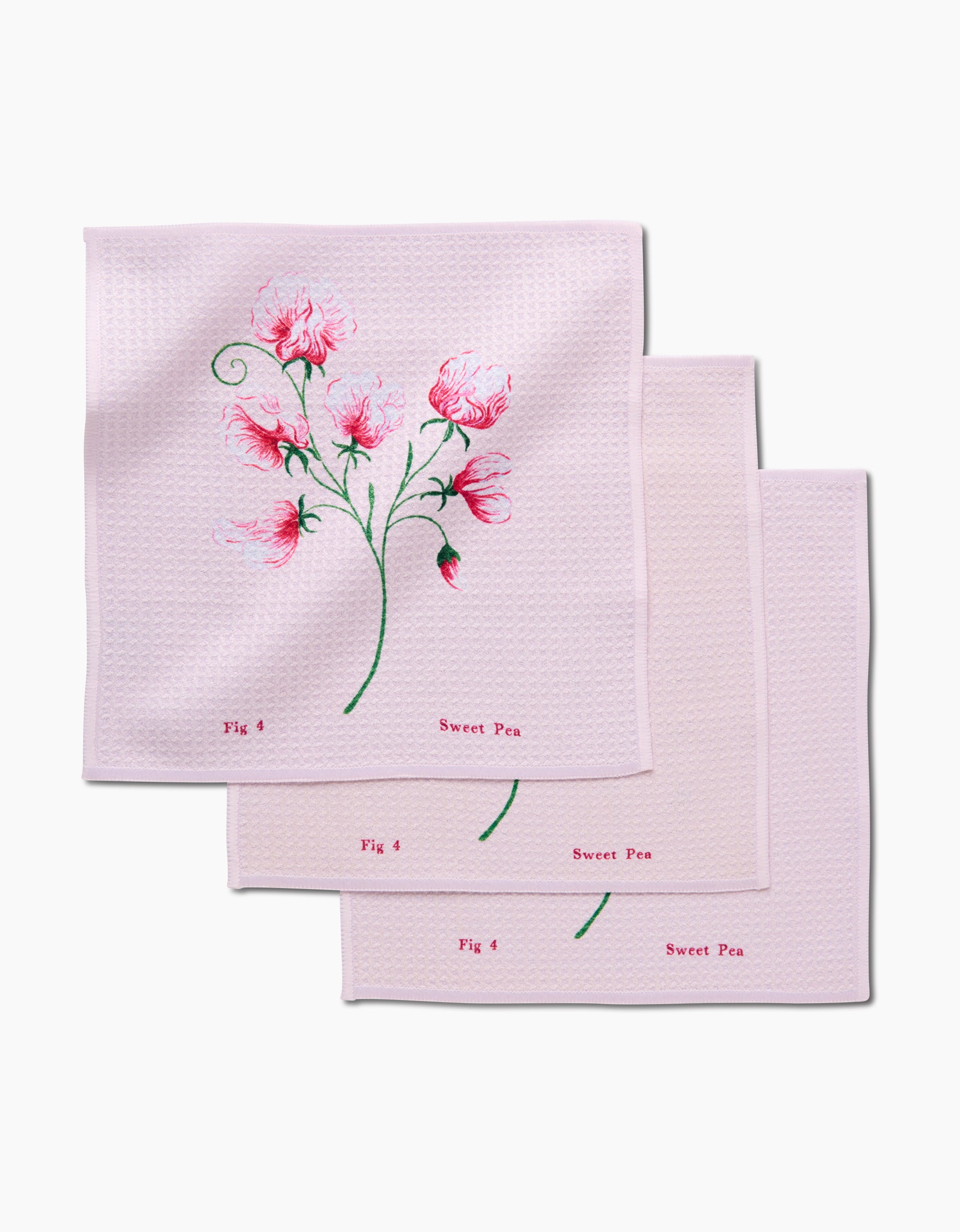 Three pale pink April Sweet Pea napkins by Linda Fox, made from recycled materials, overlap; each displays delicate pink sweet pea flowers with green stems and leaves, plus Fig 4 and Sweet Pea printed in red.