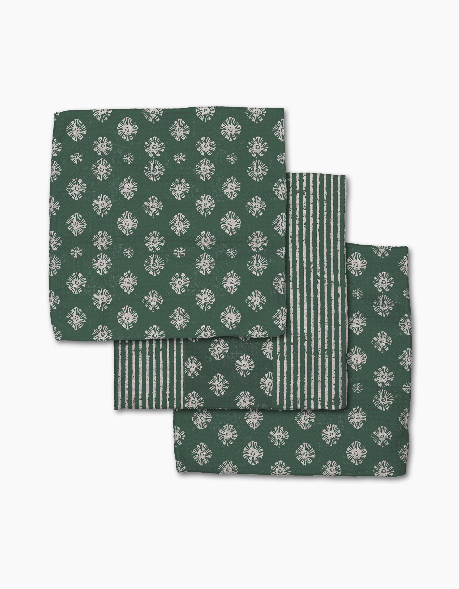 Three green Arbusto cloth napkins by Geometry, made from recycled materials with white floral and striped designs, are neatly folded and overlapping on a white background.